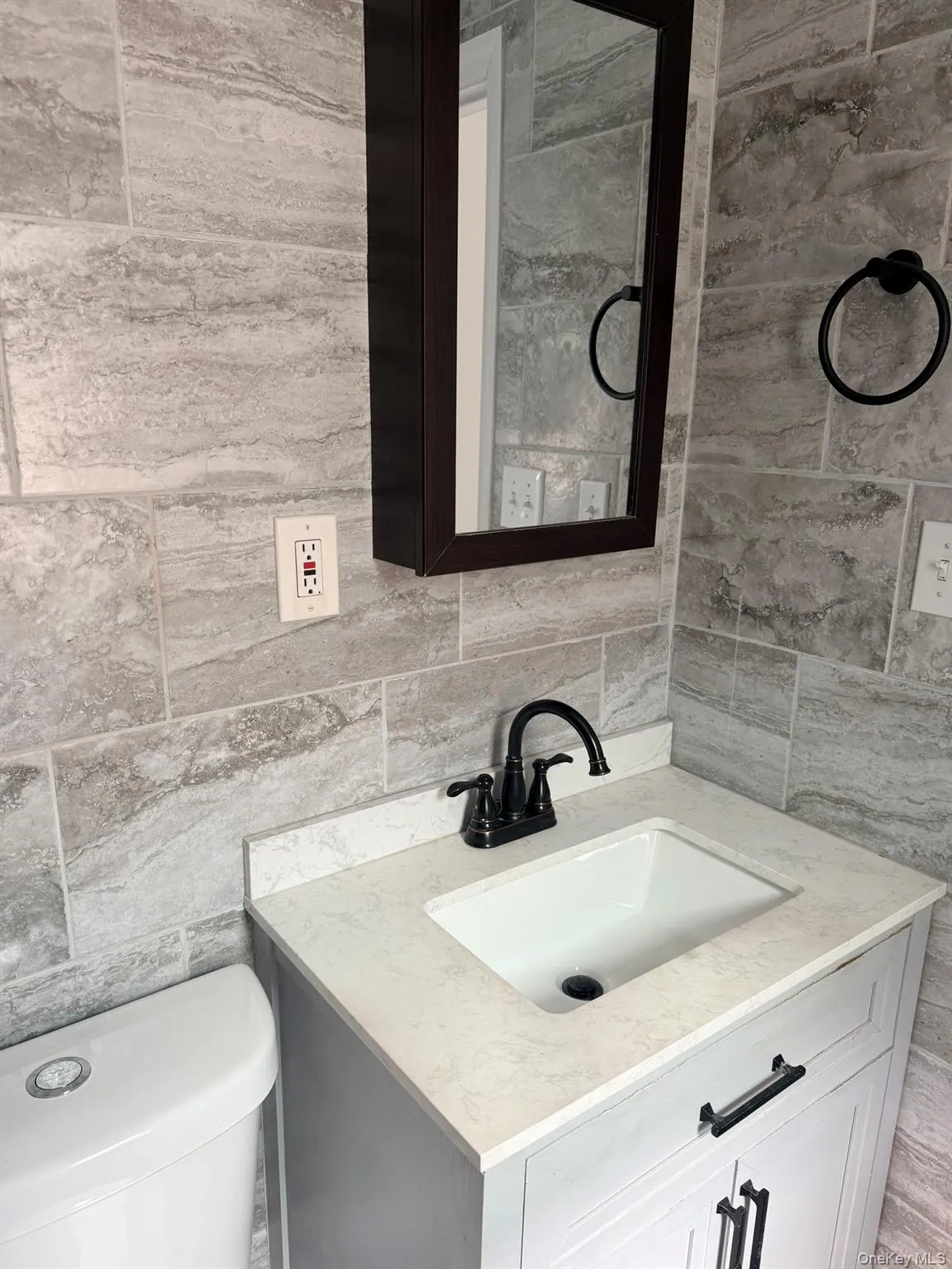 Light-toned tile walls with a dark framed medicine cabinet Light-toned tile walls with a dark framed medicine cabinet