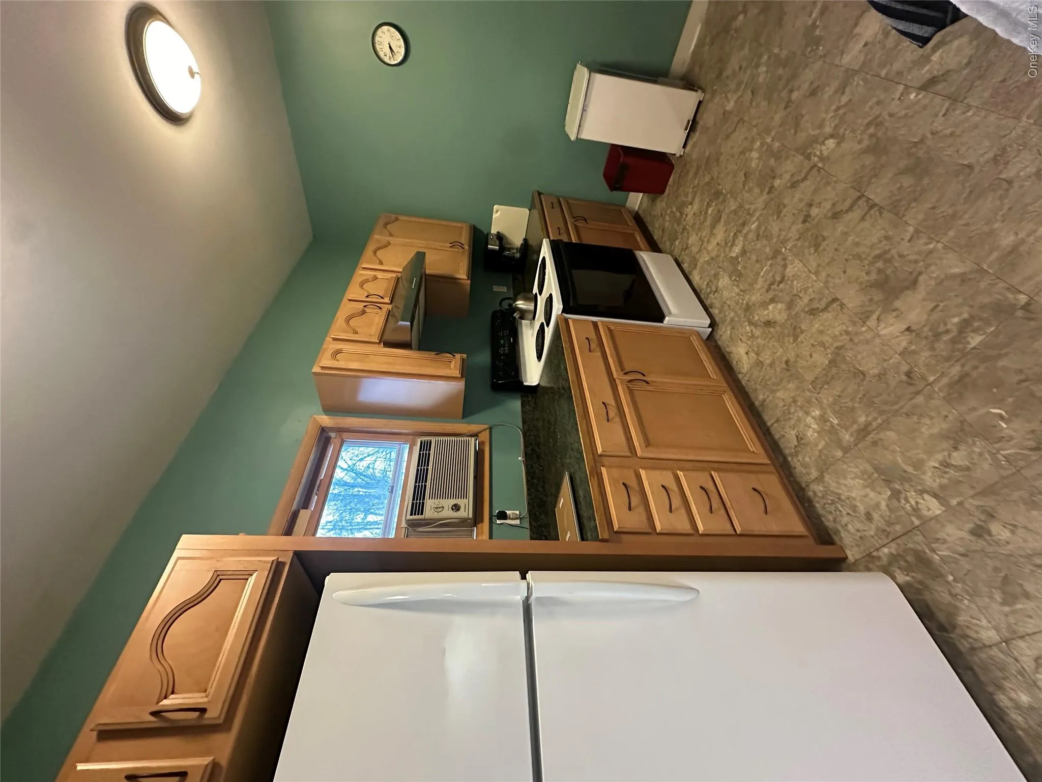 Kitchen with dark countertops, refrigerator, electric range oven, cooling unit, and extractor fan Kitchen with dark countertops, refrigerator, electric range oven, cooling unit, and extractor fan