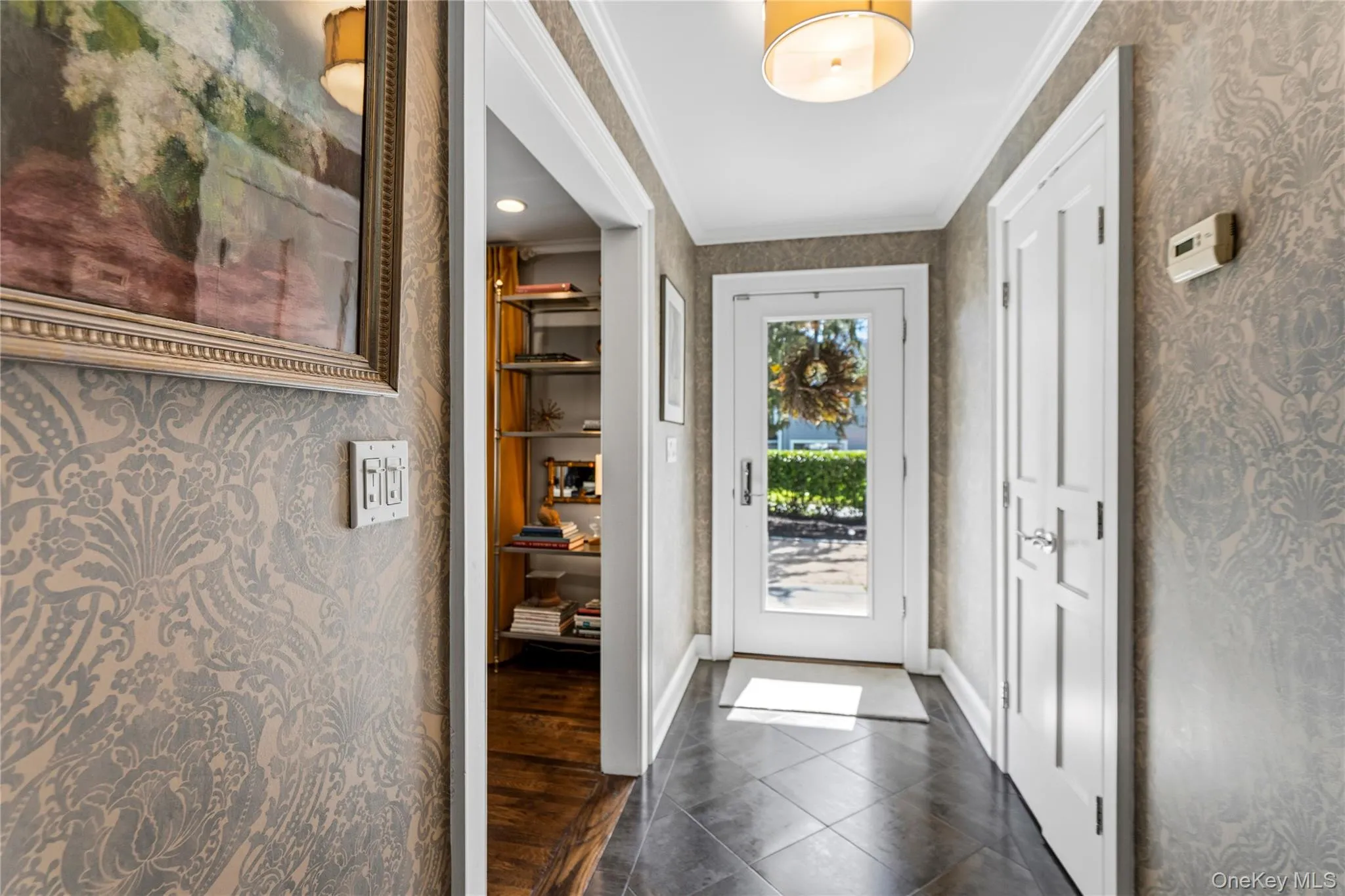 Entryway featuring patterned wallpaper, tile flooring, a glass-panel entry door, and a drum-style ceiling fixture Entryway featuring patterned wallpaper, tile flooring, a glass-panel entry door, and a drum-style ceiling fixture
