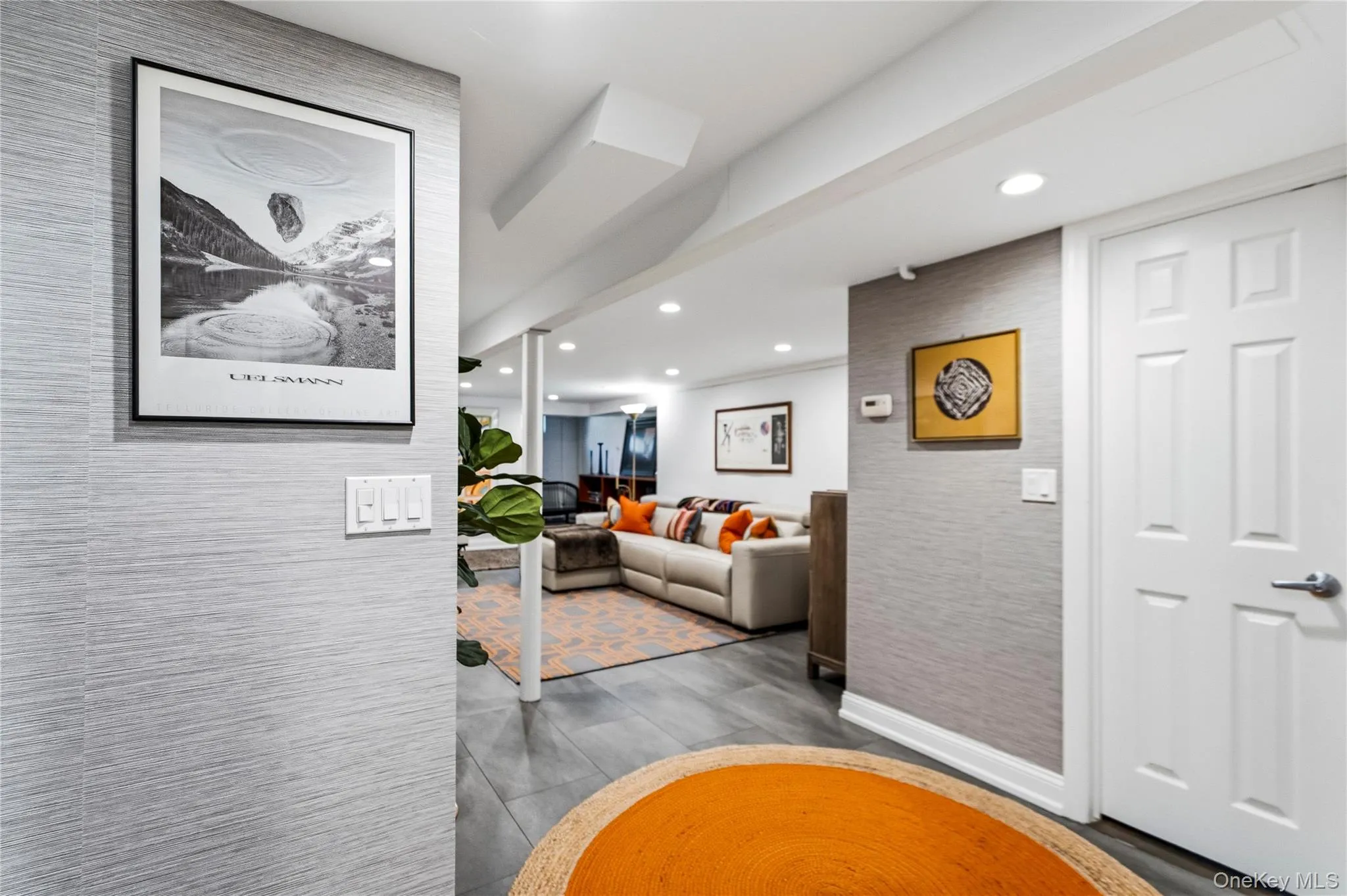 Interior space featuring textured grey wall coverings, recessed ceiling lighting, and large-format tile flooring Interior space featuring textured grey wall coverings, recessed ceiling lighting, and large-format tile flooring