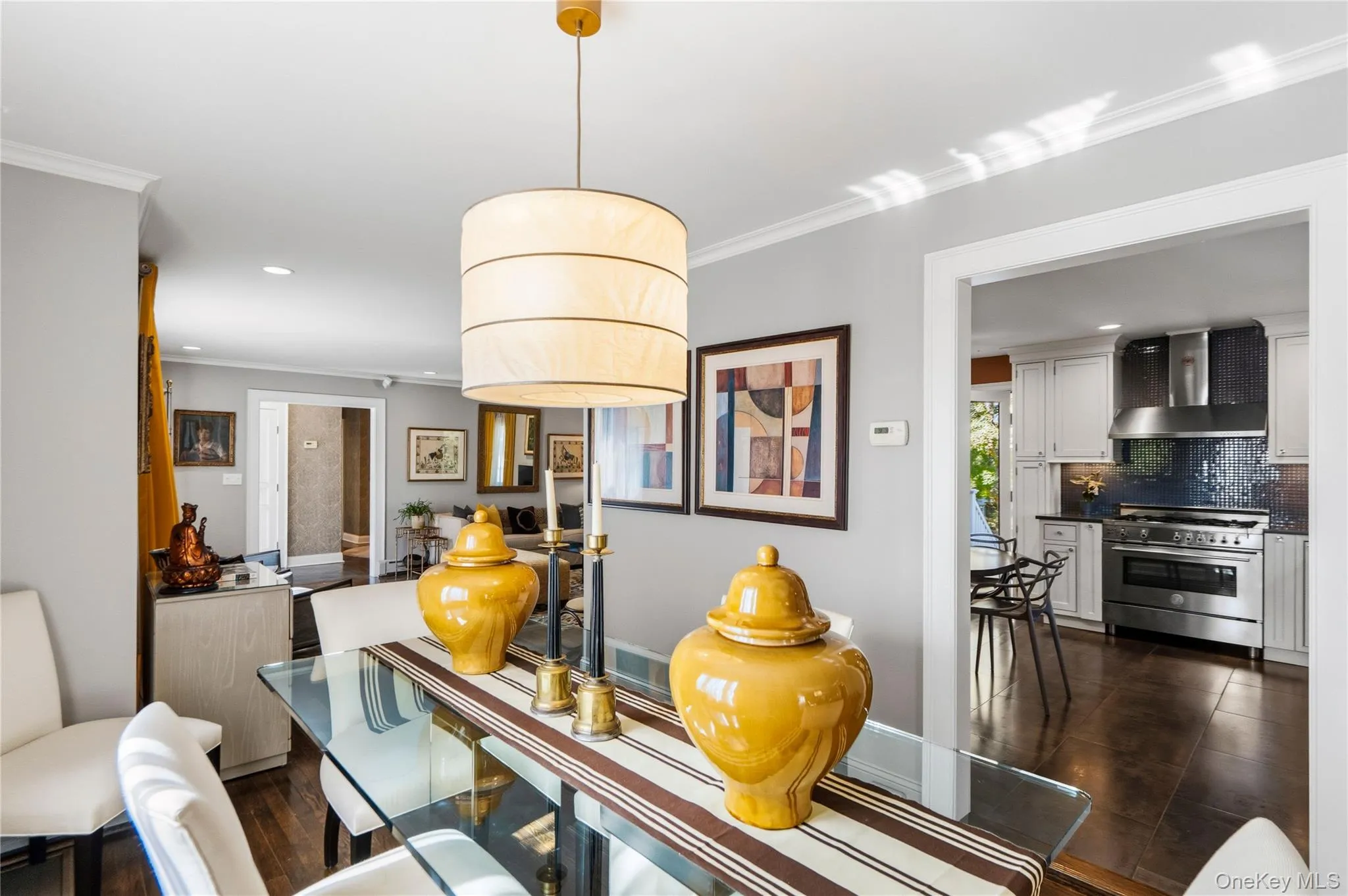 Neutral-toned interior featuring hardwood flooring, a cylindrical pendant light fixture, crown molding, and recessed lighting Neutral-toned interior featuring hardwood flooring, a cylindrical pendant light fixture, crown molding, and recessed lighting