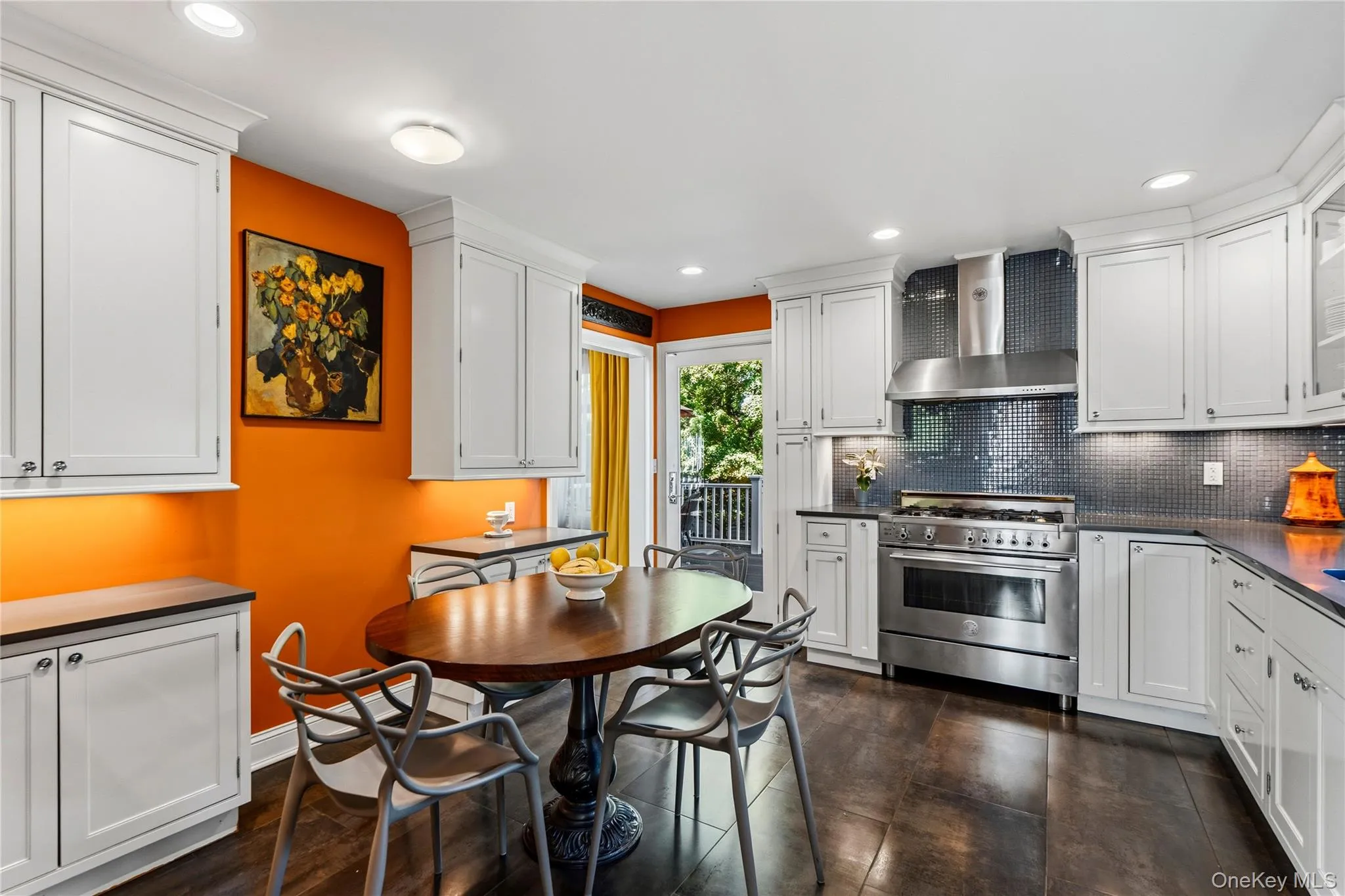 Kitchen featuring white cabinetry, stainless steel gas range with professional-style hood, dark mosaic tile backsplash, and dark tile flooring Kitchen featuring white cabinetry, stainless steel gas range with professional-style hood, dark mosaic tile backsplash, and dark tile flooring
