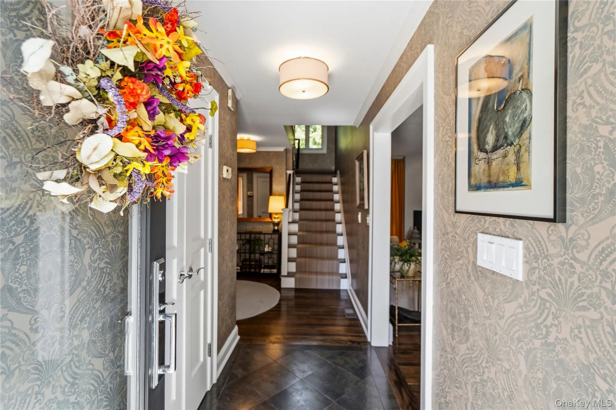 Foyer featuring damask-patterned wallpaper, dark-toned stone floor tile, wood-finish flooring, and recessed ceiling lighting Foyer featuring damask-patterned wallpaper, dark-toned stone floor tile, wood-finish flooring, and recessed ceiling lighting