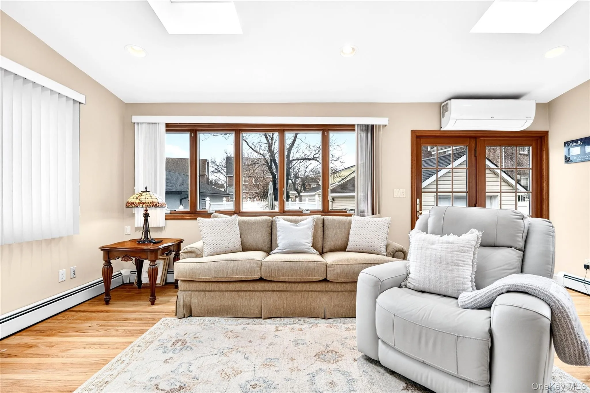 Living room featuring a skylight, light wood-style floors, a wall mounted AC, and recessed lighting Living room featuring a skylight, light wood-style floors, a wall mounted AC, and recessed lighting