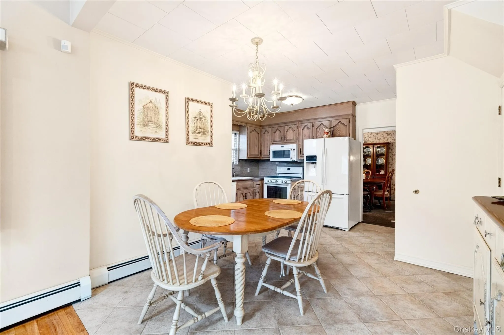 Dining space featuring a baseboard radiator, a chandelier, and light tile patterned floors Dining space featuring a baseboard radiator, a chandelier, and light tile patterned floors