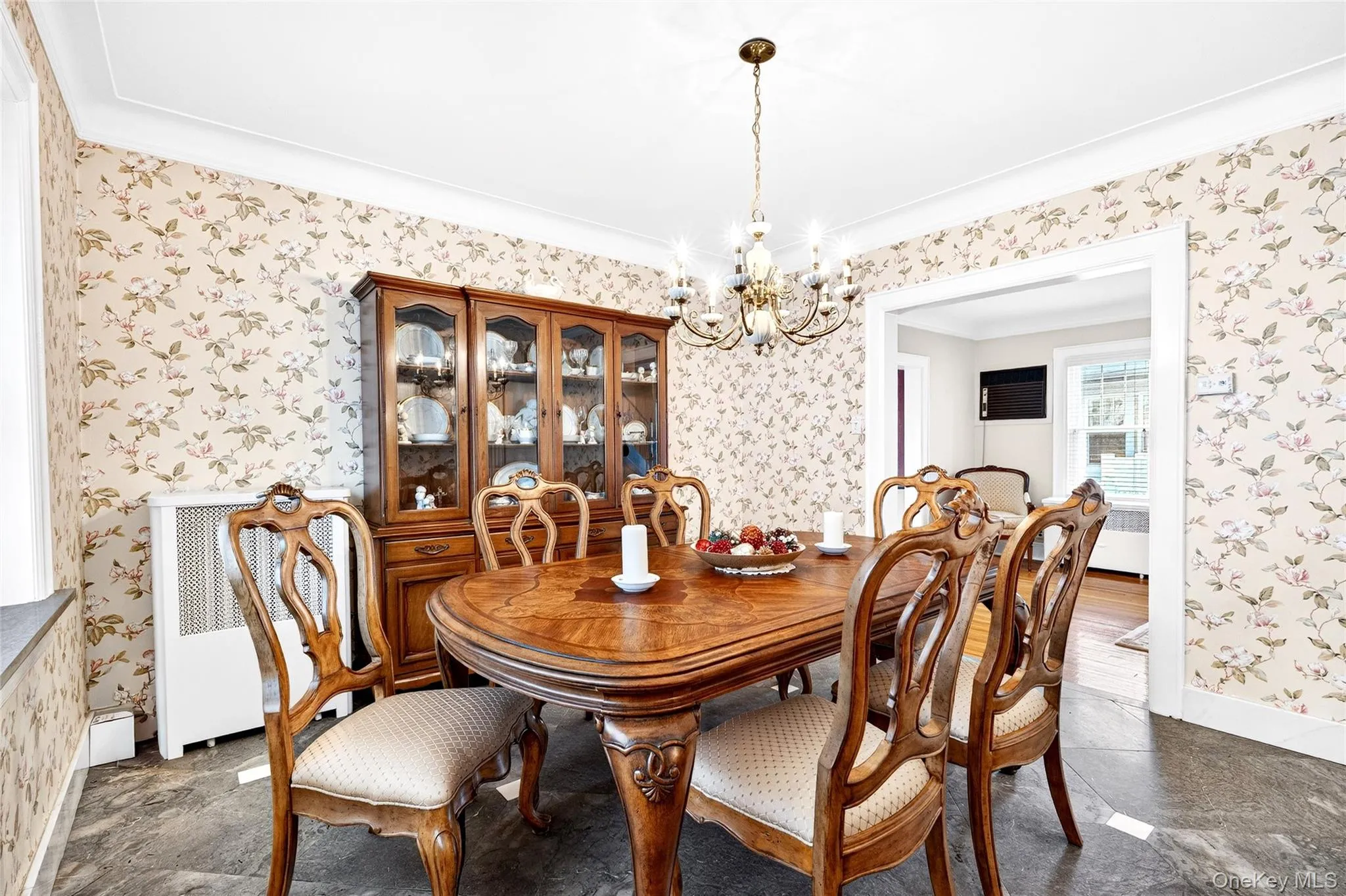 Dining room with a chandelier, radiator heating unit, wallpapered walls, and ornamental molding Dining room with a chandelier, radiator heating unit, wallpapered walls, and ornamental molding