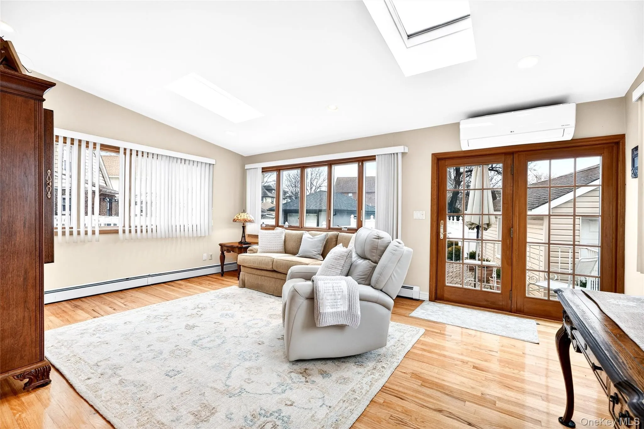 Living area with a skylight, a baseboard radiator, lofted ceiling, a wall mounted AC, and plenty of natural light Living area with a skylight, a baseboard radiator, lofted ceiling, a wall mounted AC, and plenty of natural light