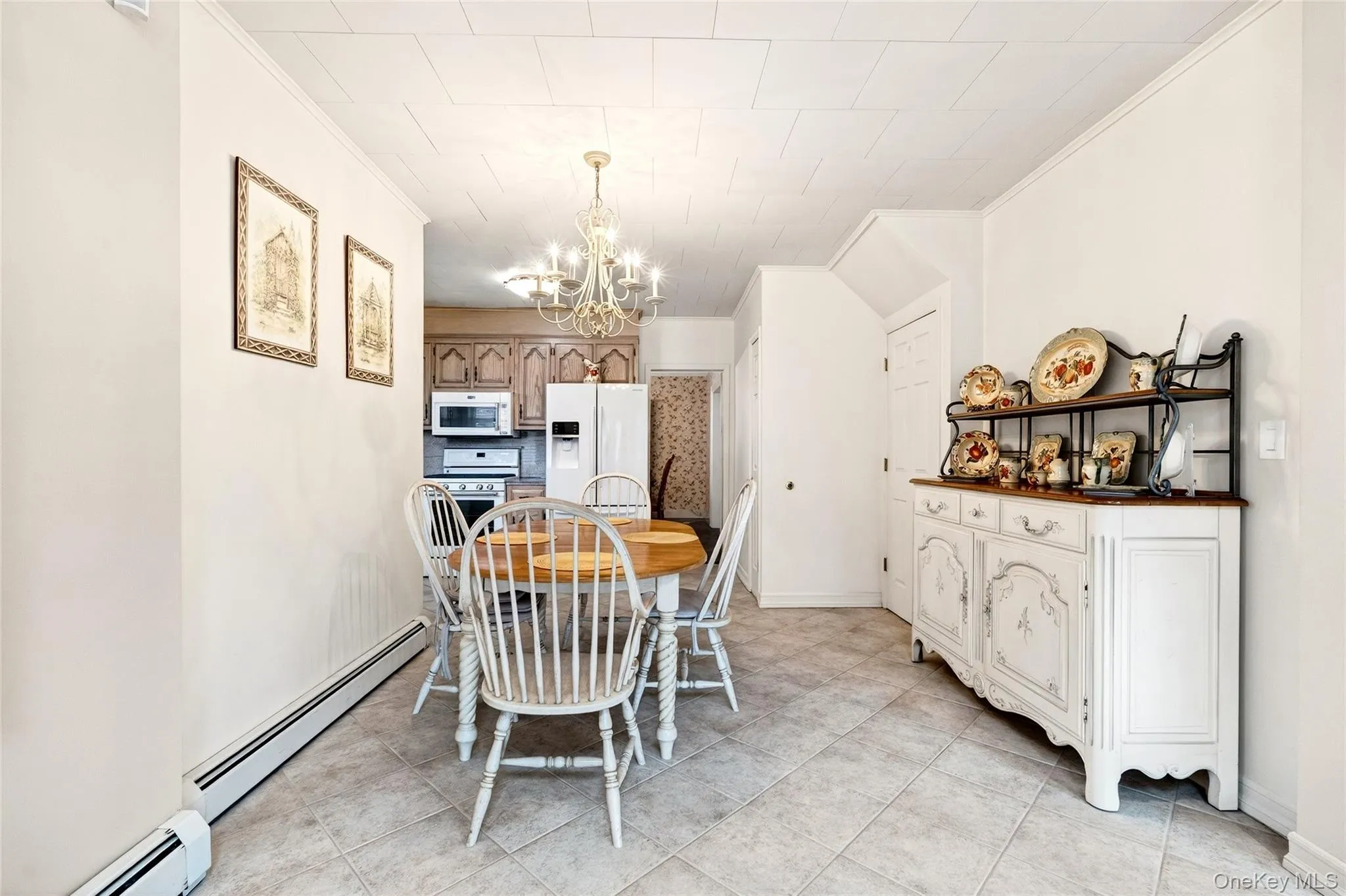 Dining room featuring a baseboard radiator, ornamental molding, a chandelier, and light tile patterned floors Dining room featuring a baseboard radiator, ornamental molding, a chandelier, and light tile patterned floors