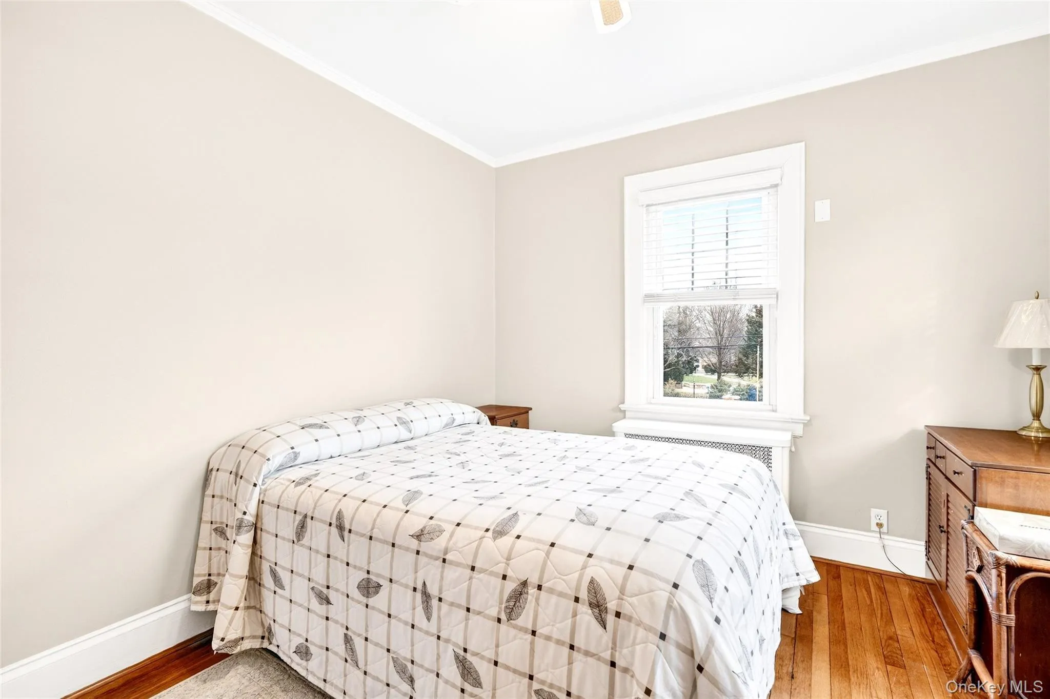 Bedroom featuring ornamental molding, light wood-style floors, radiator, and a ceiling fan Bedroom featuring ornamental molding, light wood-style floors, radiator, and a ceiling fan
