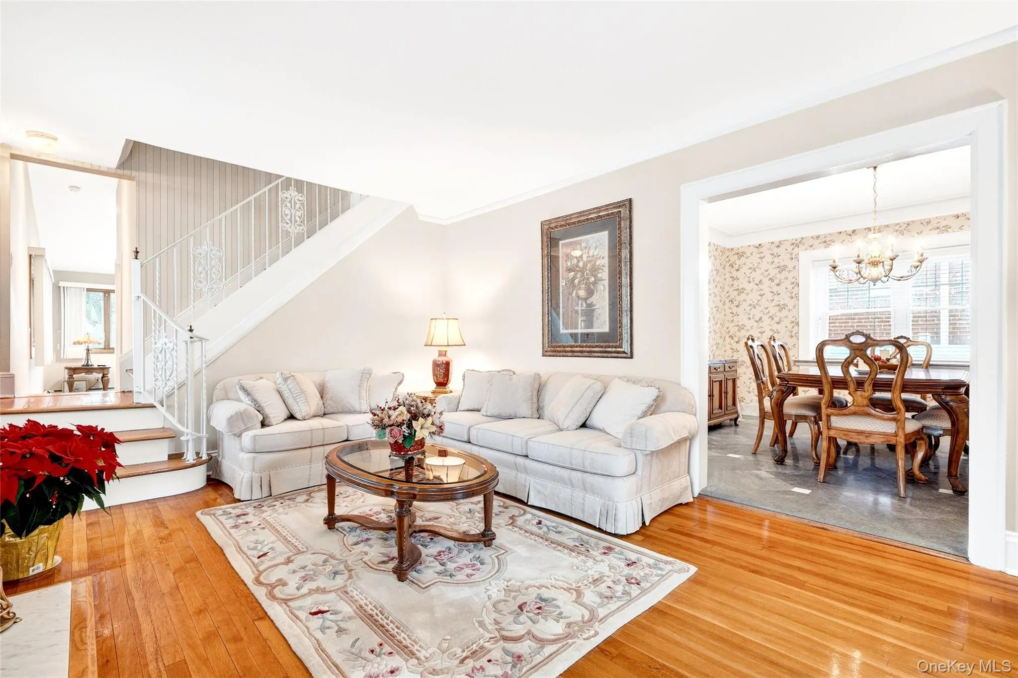Living area featuring crown molding, stairway, a chandelier, and wood-type flooring Living area featuring crown molding, stairway, a chandelier, and wood-type flooring
