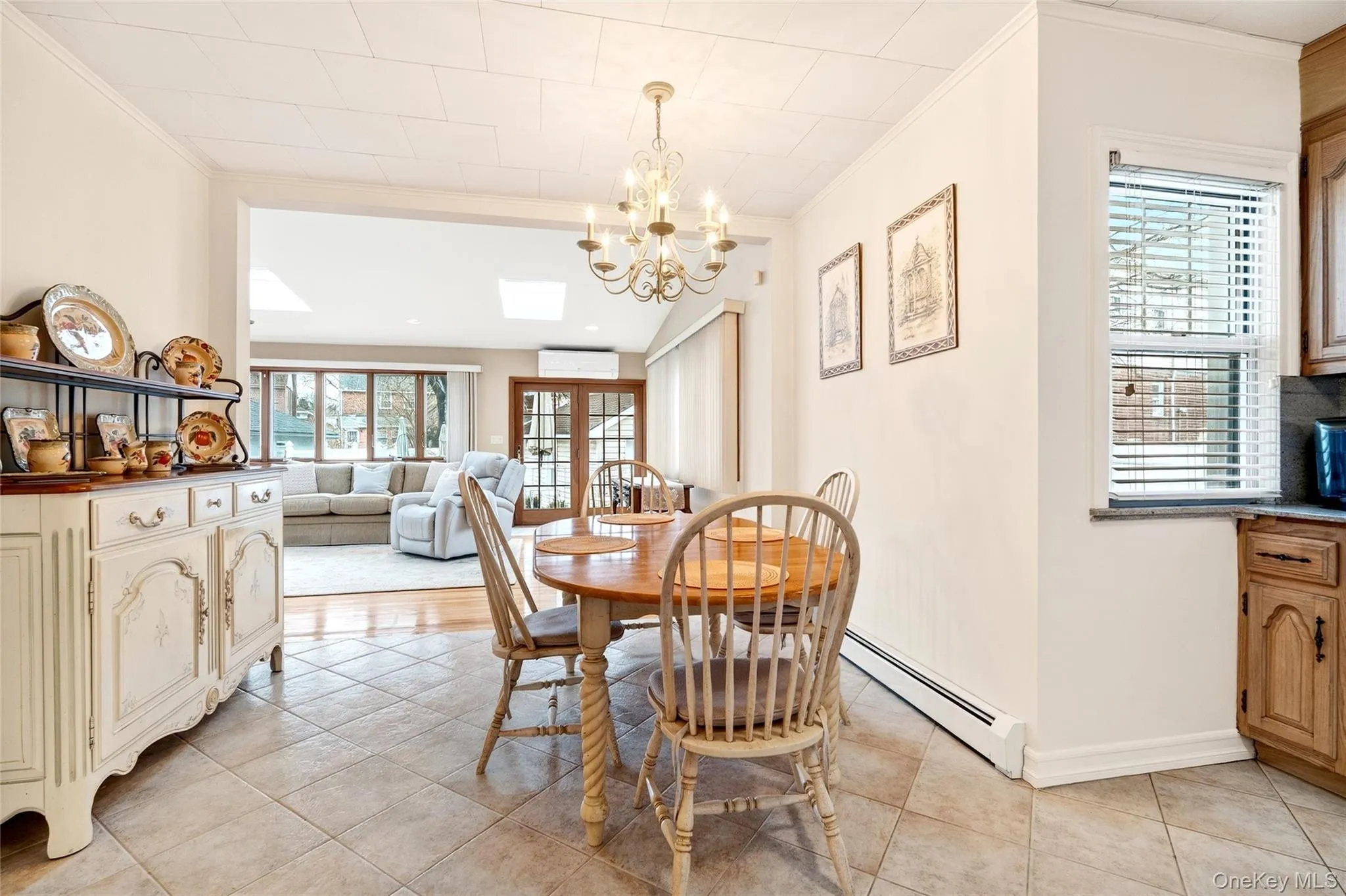 Dining area featuring a chandelier, light tile patterned floors, ornamental molding, french doors, and a skylight Dining area featuring a chandelier, light tile patterned floors, ornamental molding, french doors, and a skylight