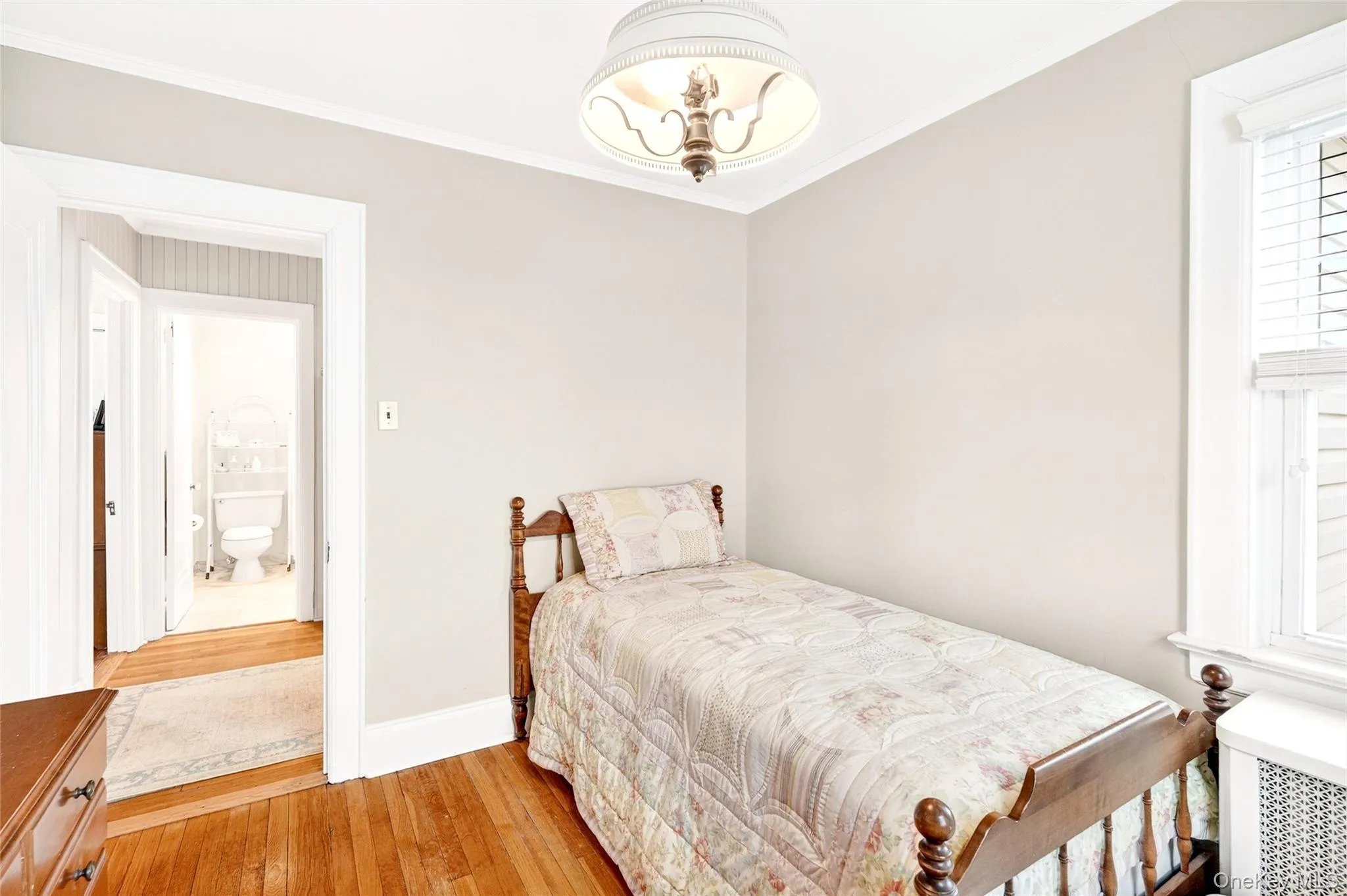 Bedroom with radiator, light wood-type flooring, and crown molding Bedroom with radiator, light wood-type flooring, and crown molding