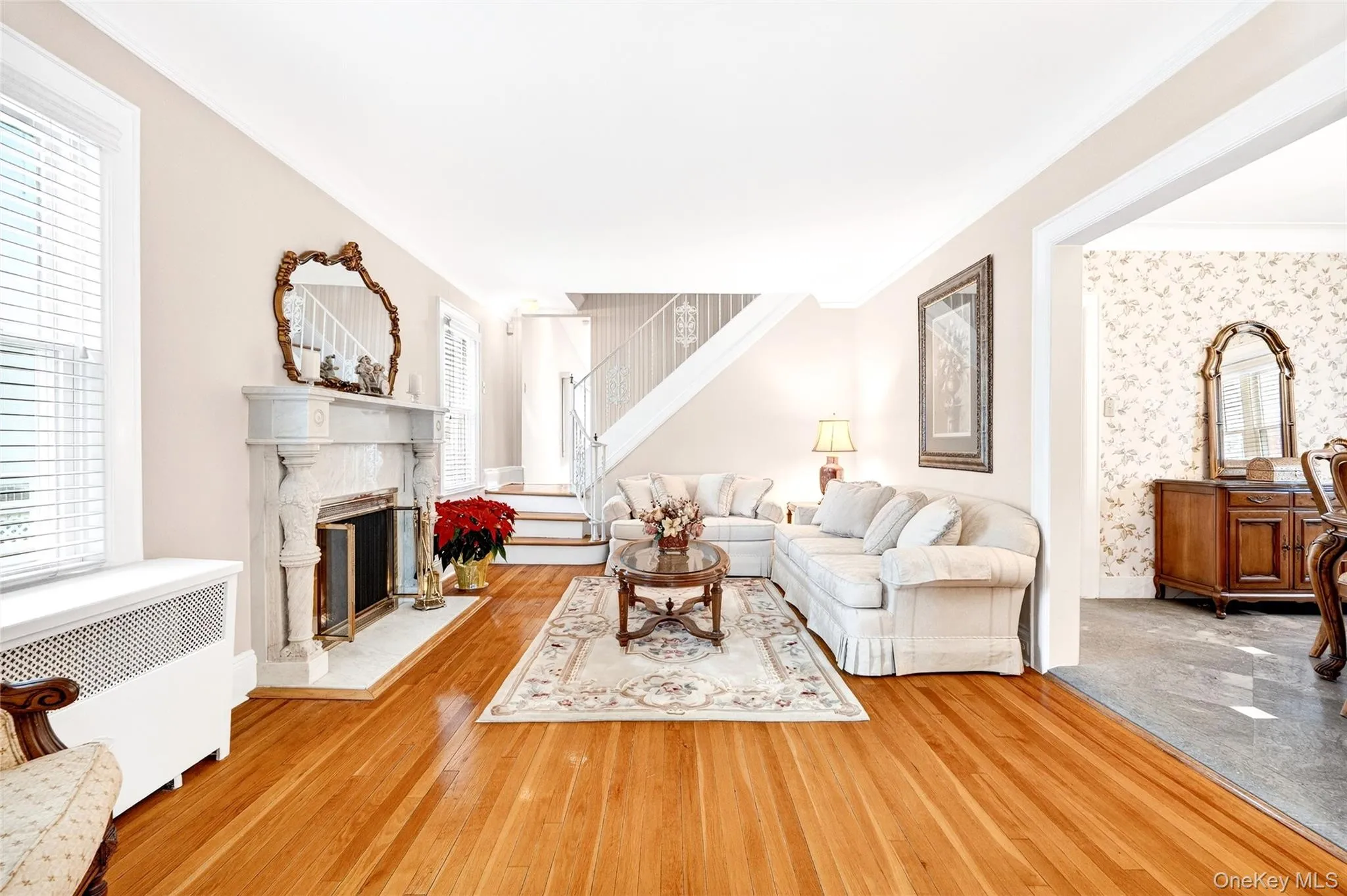Living area with radiator heating unit, crown molding, wallpapered walls, a glass covered fireplace, and hardwood / wood-style floors Living area with radiator heating unit, crown molding, wallpapered walls, a glass covered fireplace, and hardwood / wood-style floors