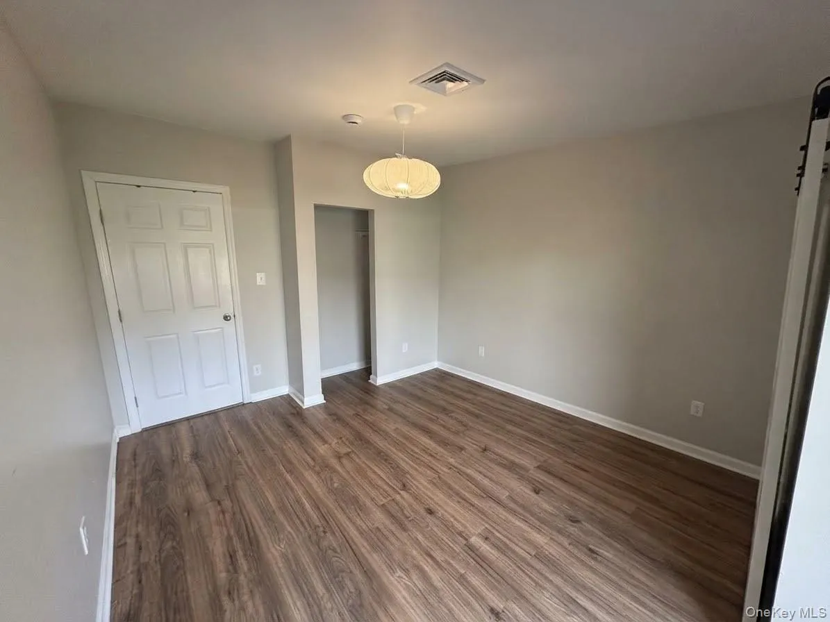 Wood-finish flooring, neutral wall paint, and a built-in closet area Wood-finish flooring, neutral wall paint, and a built-in closet area