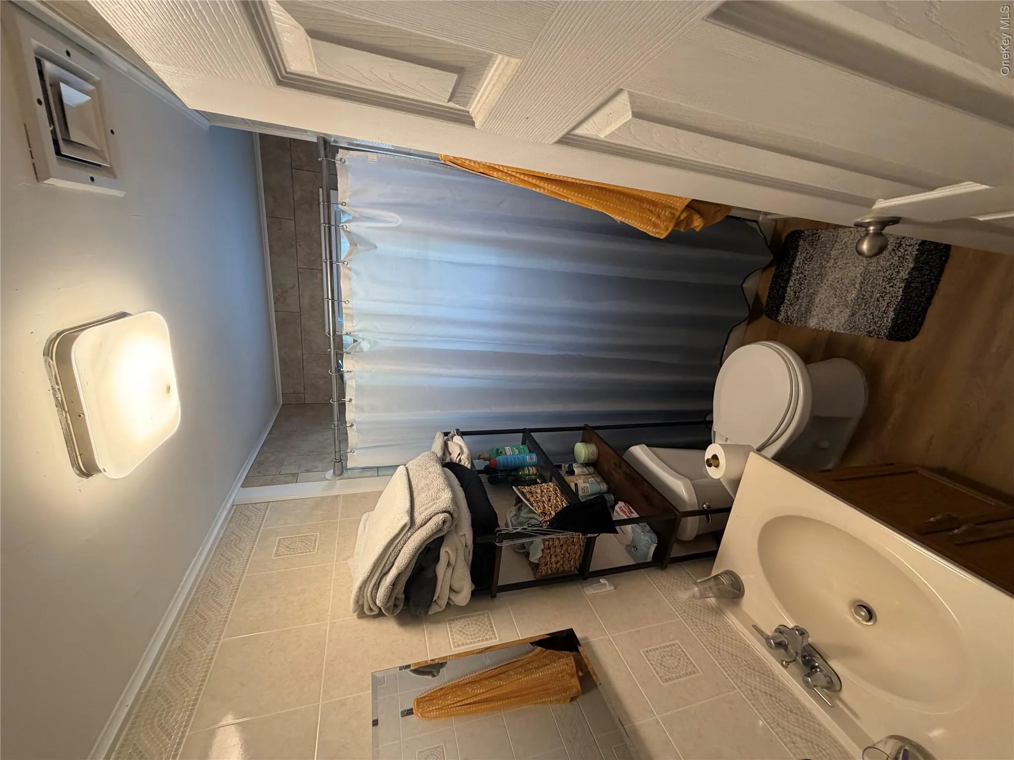 Bathroom featuring wood-finish flooring, tiled walls, a vanity with an integrated sink, a toilet, and a shower with a curtain rod Bathroom featuring wood-finish flooring, tiled walls, a vanity with an integrated sink, a toilet, and a shower with a curtain rod