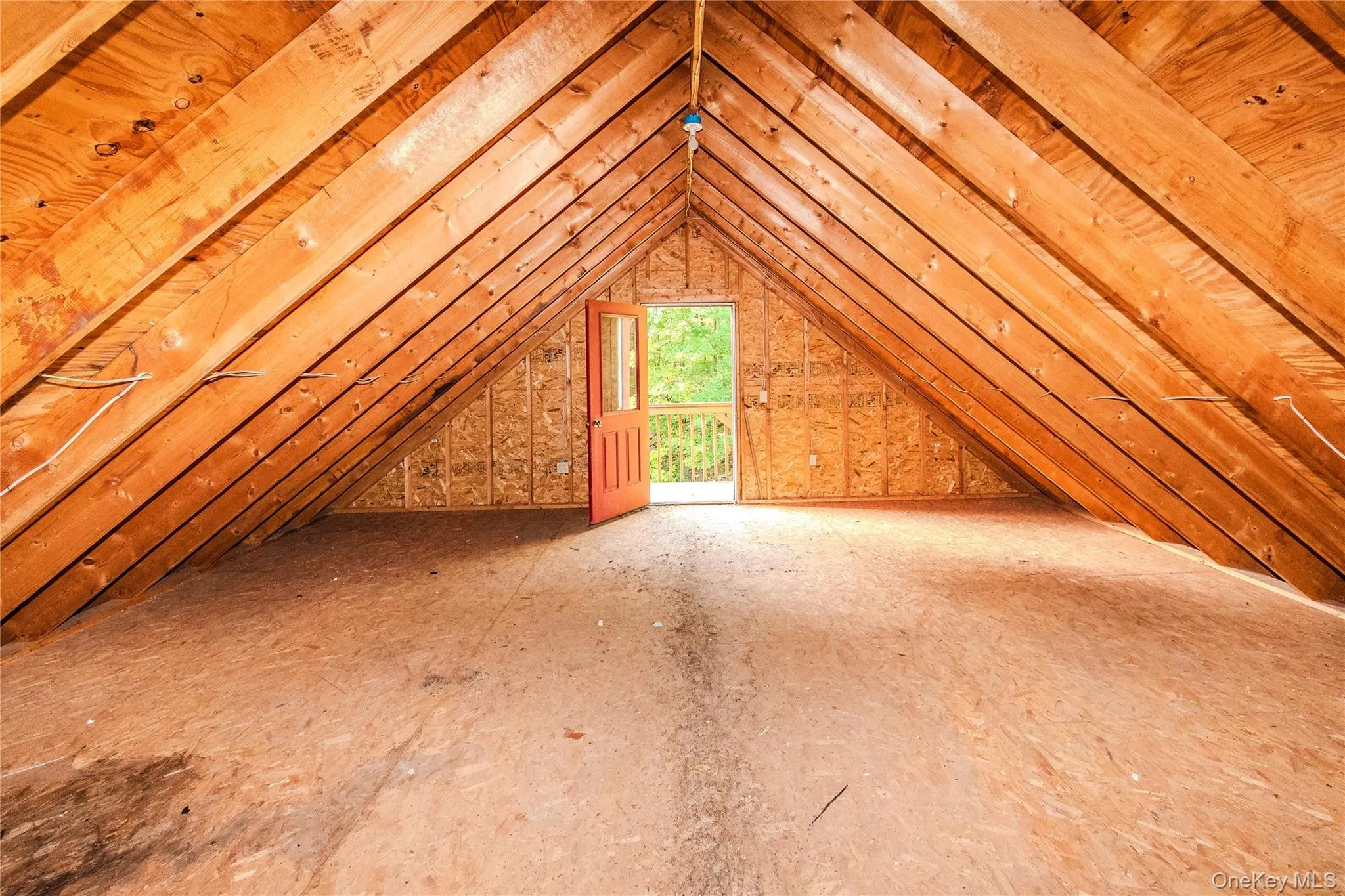 Vaulted wood beam ceiling, exposed wood rafters, wood paneling, open doorway, and outdoor balcony with railing Vaulted wood beam ceiling, exposed wood rafters, wood paneling, open doorway, and outdoor balcony with railing