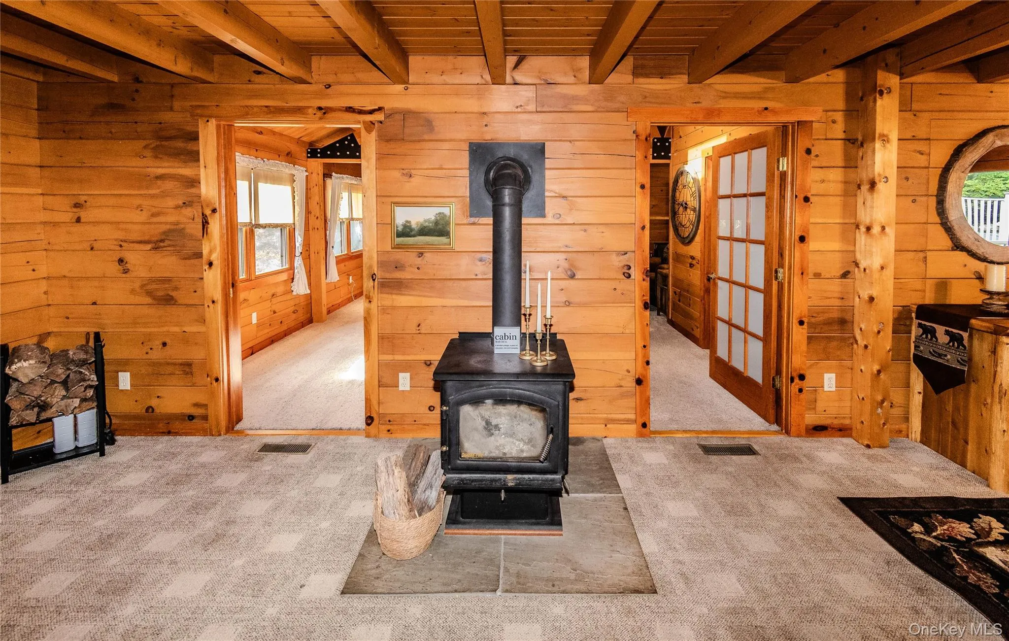 Wood paneling throughout, exposed wood beam ceiling, central wood-burning stove, and two frosted glass French doors Wood paneling throughout, exposed wood beam ceiling, central wood-burning stove, and two frosted glass French doors