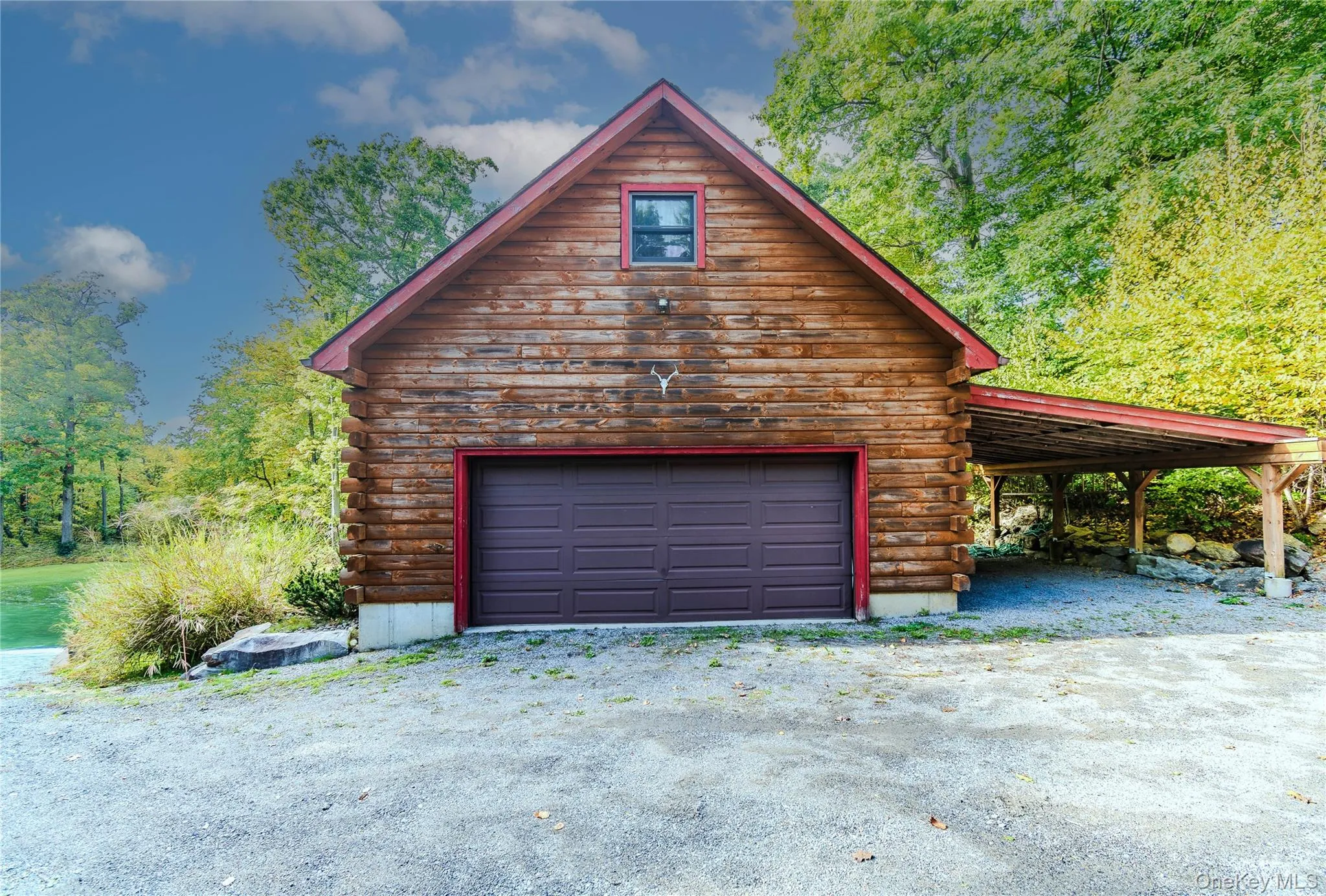 Log cabin exterior with a pitched roof, a paneled garage door, an upper-level window, and an attached covered carport Log cabin exterior with a pitched roof, a paneled garage door, an upper-level window, and an attached covered carport