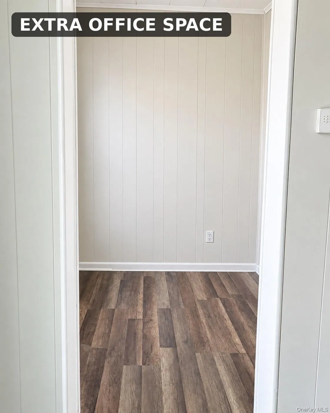 Wood-finish flooring with white baseboards and light-colored paneled walls Wood-finish flooring with white baseboards and light-colored paneled walls