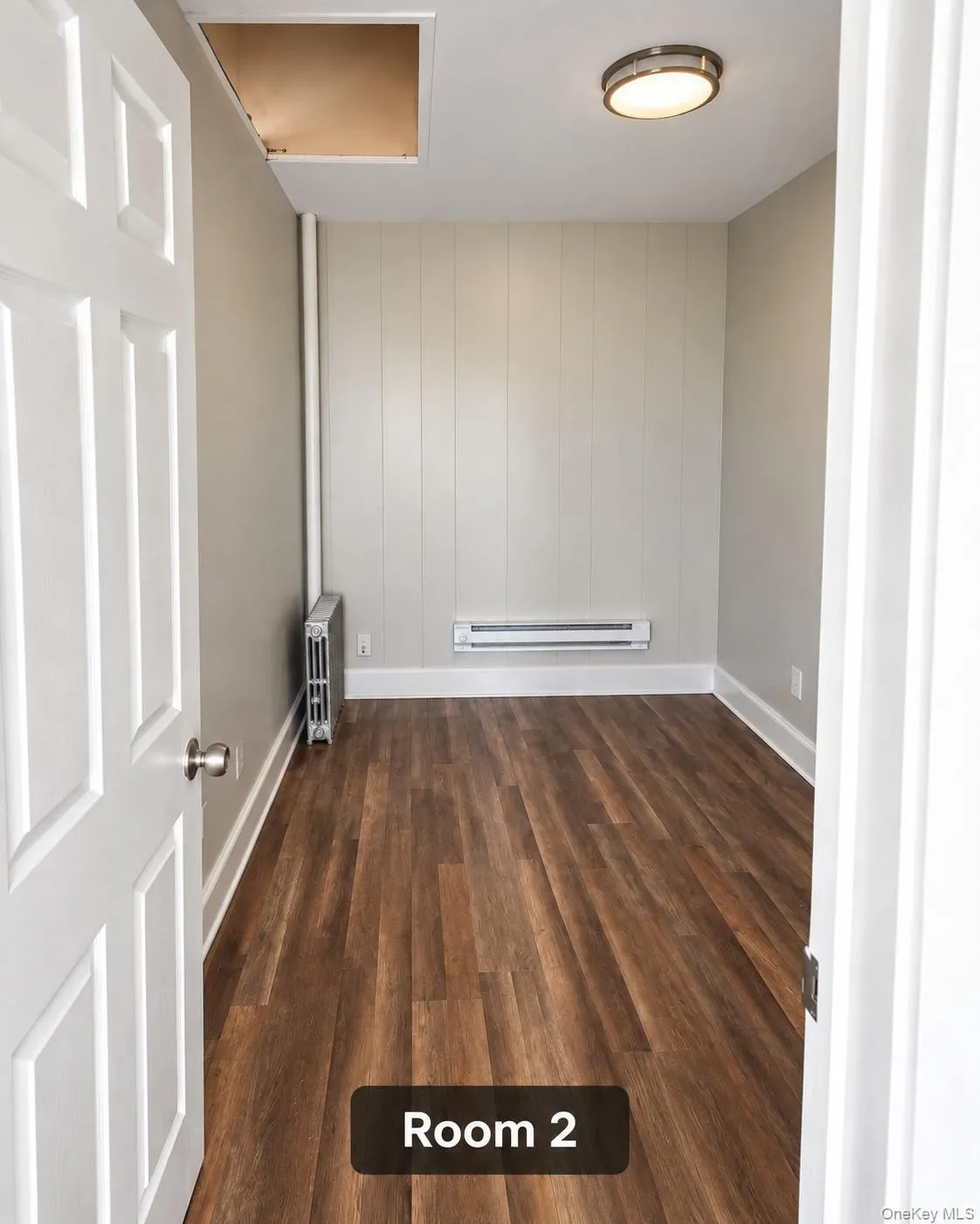 Wood-finish flooring with baseboard heating and a ceiling-mounted light fixture Wood-finish flooring with baseboard heating and a ceiling-mounted light fixture