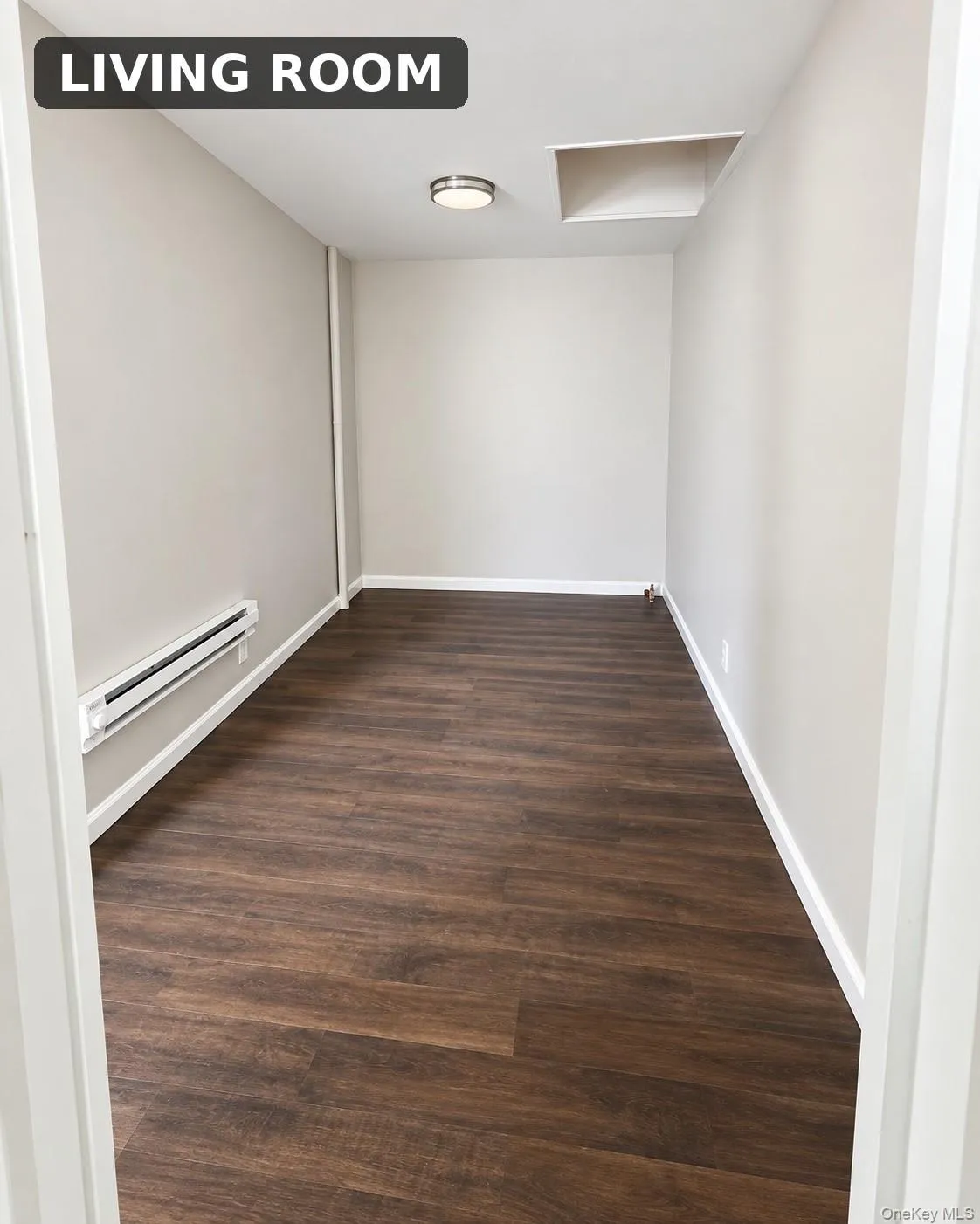 Wood-finish flooring, neutral wall tones, baseboard heating, recessed ceiling light, and attic access Wood-finish flooring, neutral wall tones, baseboard heating, recessed ceiling light, and attic access