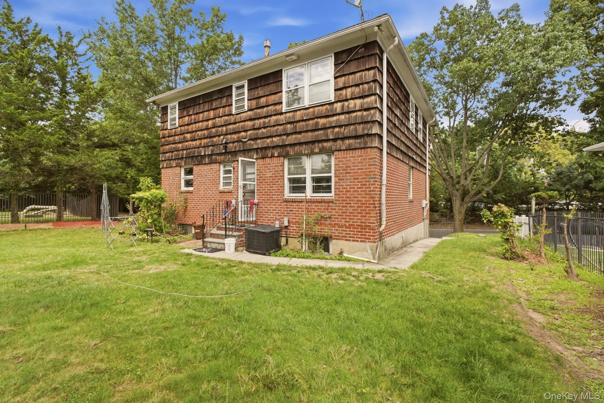 Brick and wood-shingle exterior with multiple windows and a grassy yard Brick and wood-shingle exterior with multiple windows and a grassy yard