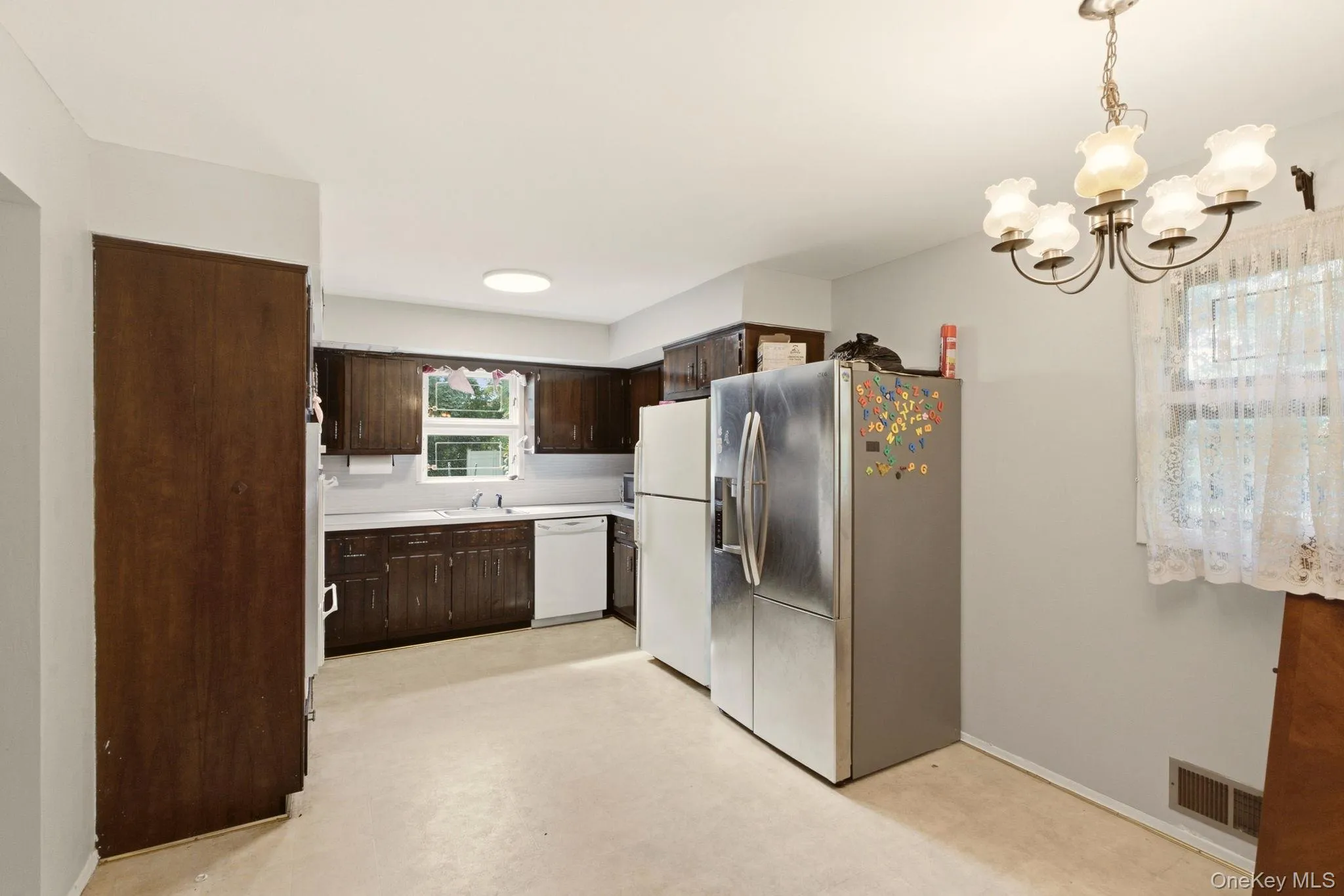 Kitchen featuring wood-finish cabinetry, light-toned countertops, and a ceiling-mounted light fixture Kitchen featuring wood-finish cabinetry, light-toned countertops, and a ceiling-mounted light fixture