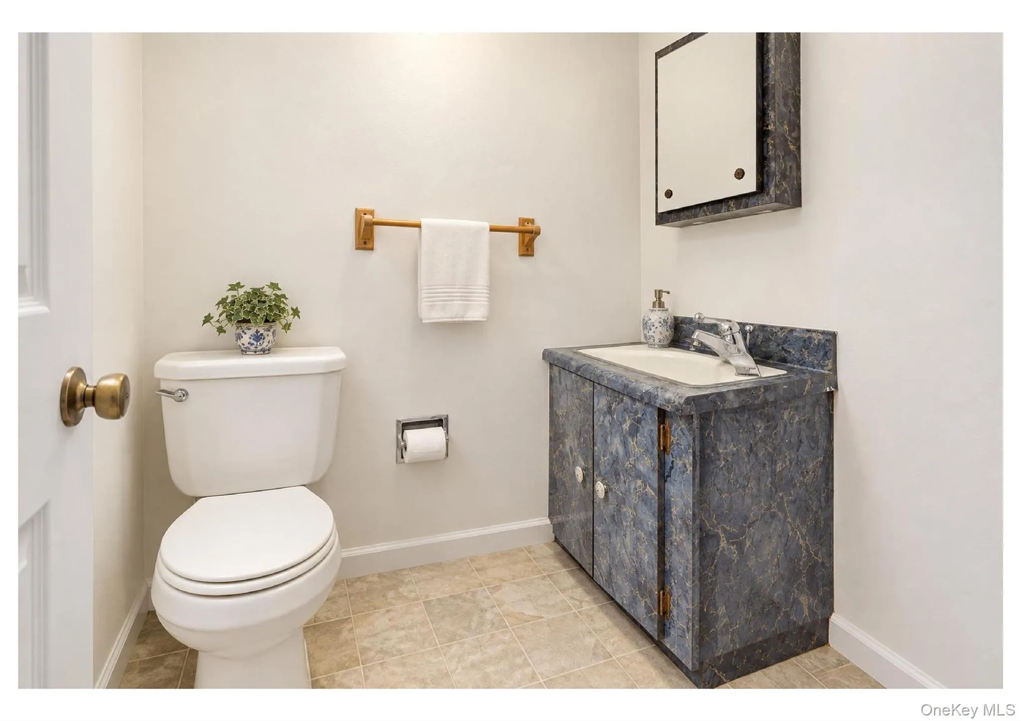 Compact bathroom featuring a vanity with an integrated sink, wall-mounted mirrored medicine cabinet, and tile flooring Compact bathroom featuring a vanity with an integrated sink, wall-mounted mirrored medicine cabinet, and tile flooring