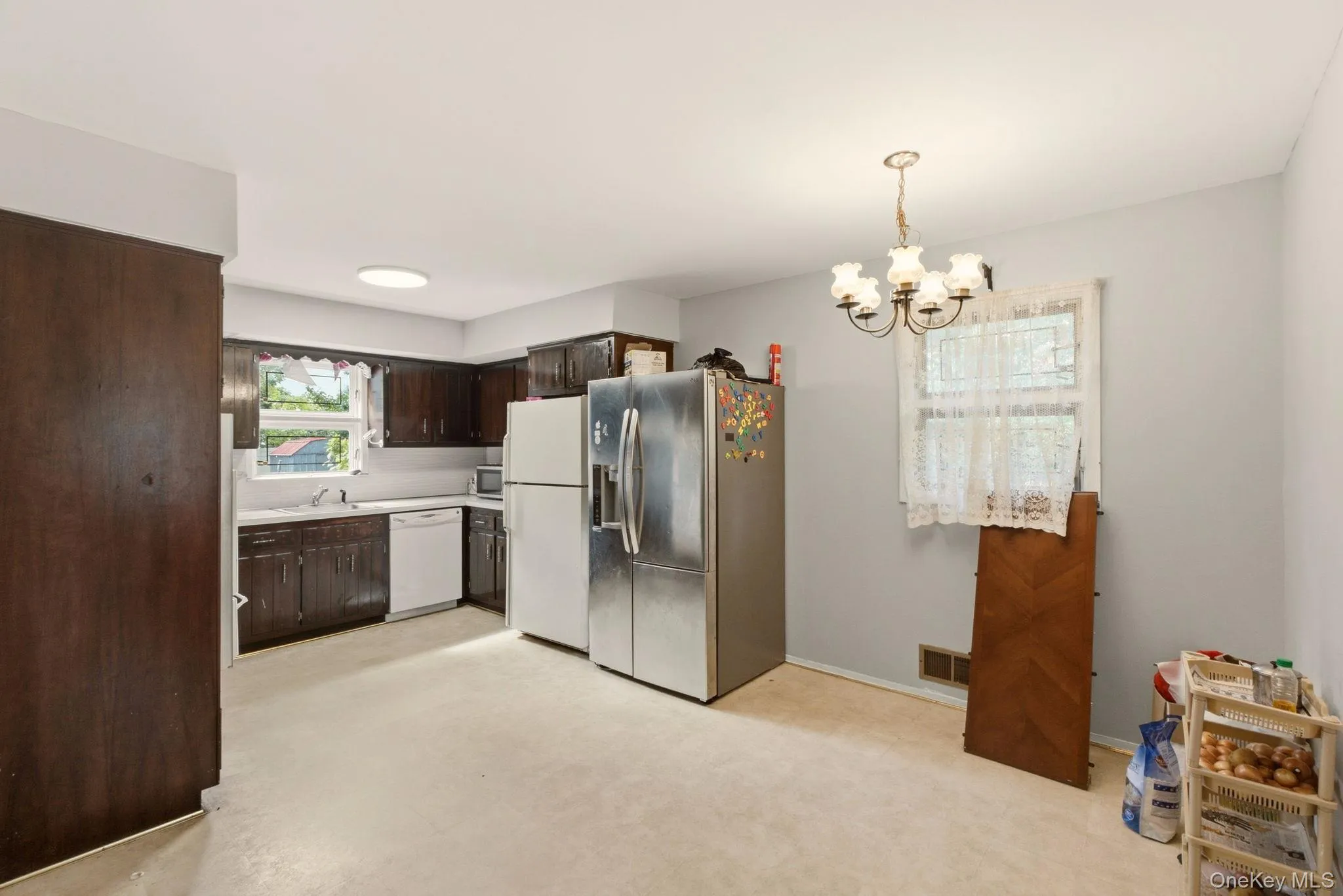 Kitchen featuring dark wood cabinetry, white appliances, and a window above the sink Kitchen featuring dark wood cabinetry, white appliances, and a window above the sink