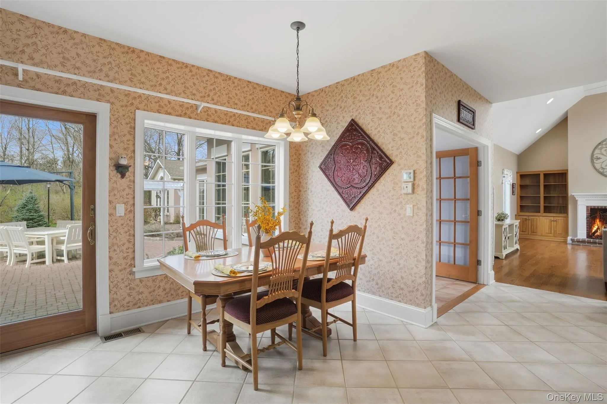 The dining area features tiled flooring, a decorative chandelier, and a window offering views of the exterior patio The dining area features tiled flooring, a decorative chandelier, and a window offering views of the exterior patio