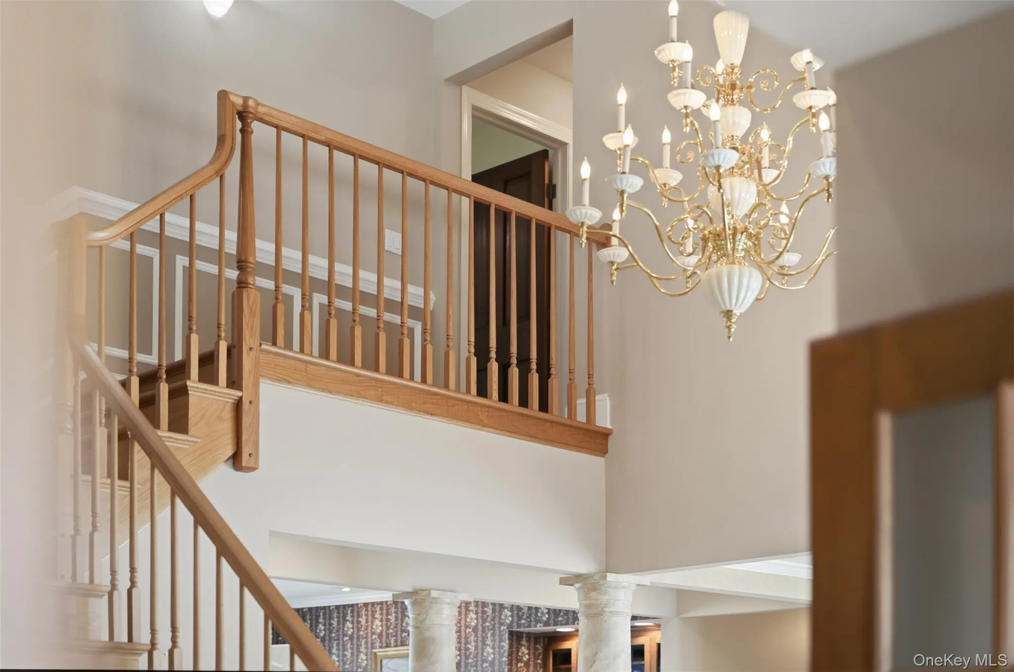 Grand entryway featuring a detailed chandelier, a wooden staircase, and decorative wall molding Grand entryway featuring a detailed chandelier, a wooden staircase, and decorative wall molding