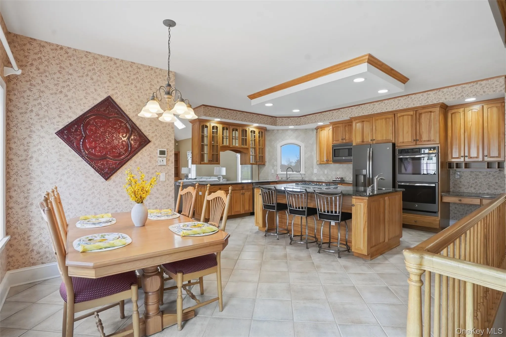 This property features a kitchen and dining area with hardwood cabinetry, a kitchen island with seating, a large refrigerator, and a double oven This property features a kitchen and dining area with hardwood cabinetry, a kitchen island with seating, a large refrigerator, and a double oven