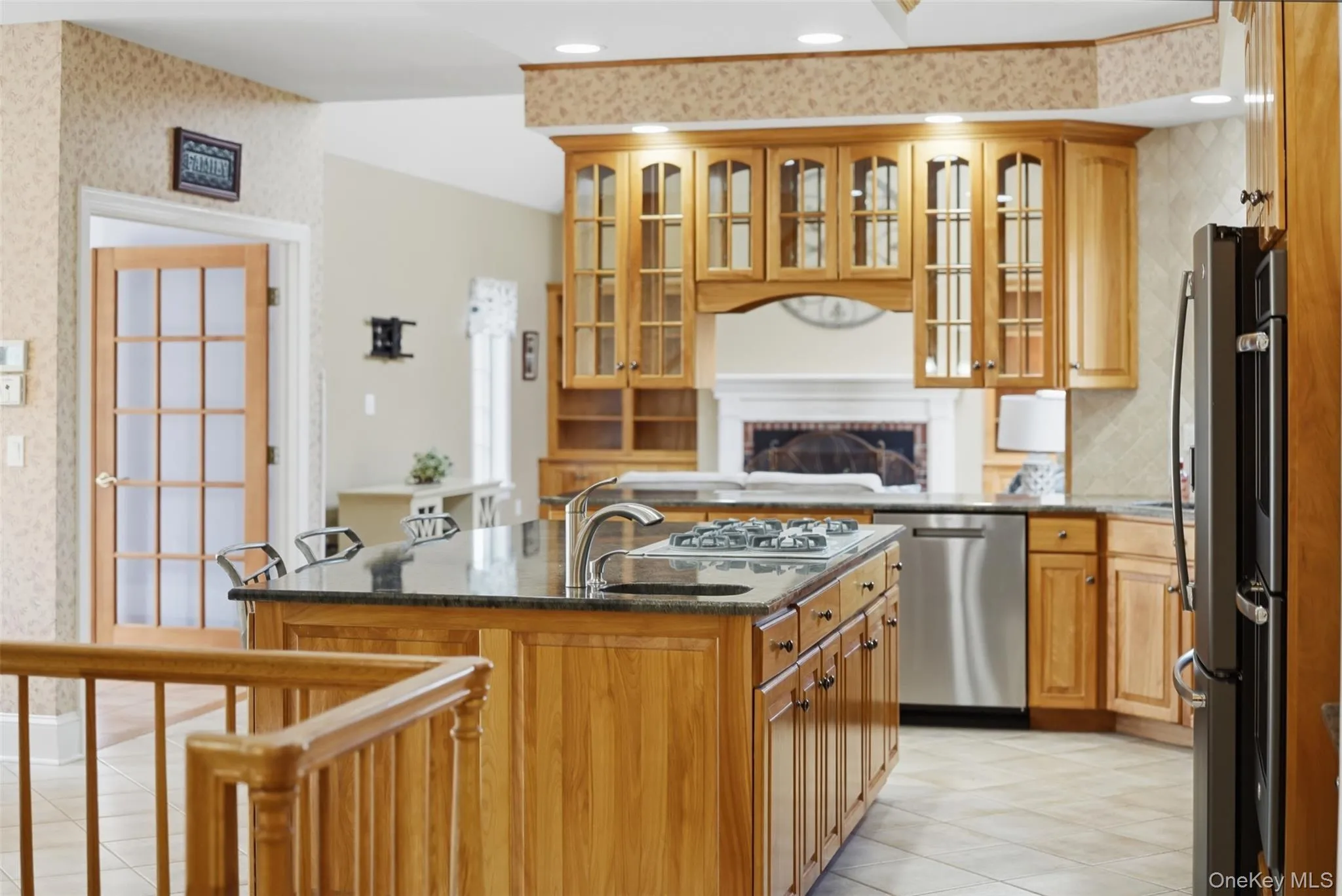The kitchen features a central island with a sink and stovetop, wood cabinetry, and stainless steel appliances The kitchen features a central island with a sink and stovetop, wood cabinetry, and stainless steel appliances