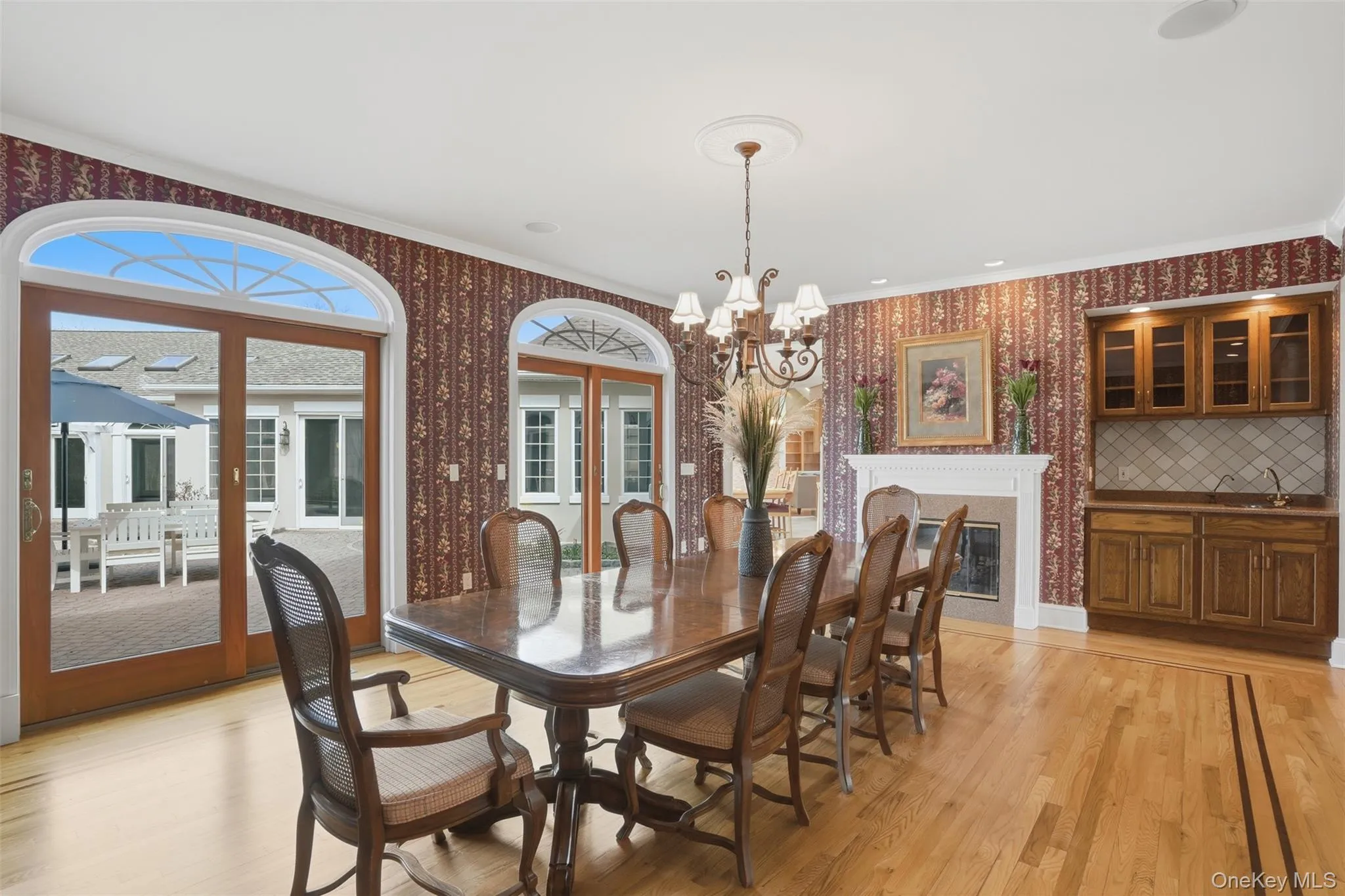 This dining area features hardwood floors, a decorative fireplace, and a built-in wet bar with wood cabinetry and a tiled backsplash This dining area features hardwood floors, a decorative fireplace, and a built-in wet bar with wood cabinetry and a tiled backsplash