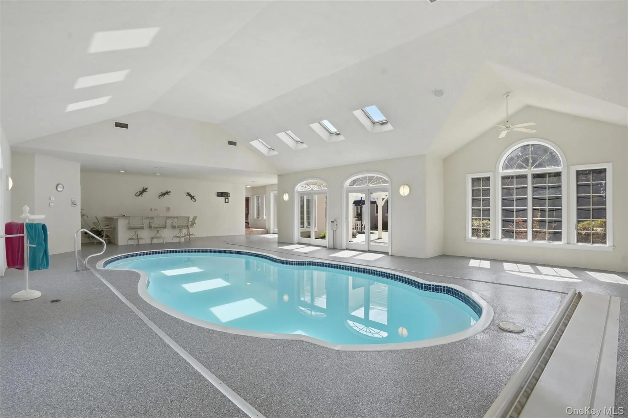 Indoor swimming pool area with skylights, large windows, and a vaulted ceiling Indoor swimming pool area with skylights, large windows, and a vaulted ceiling