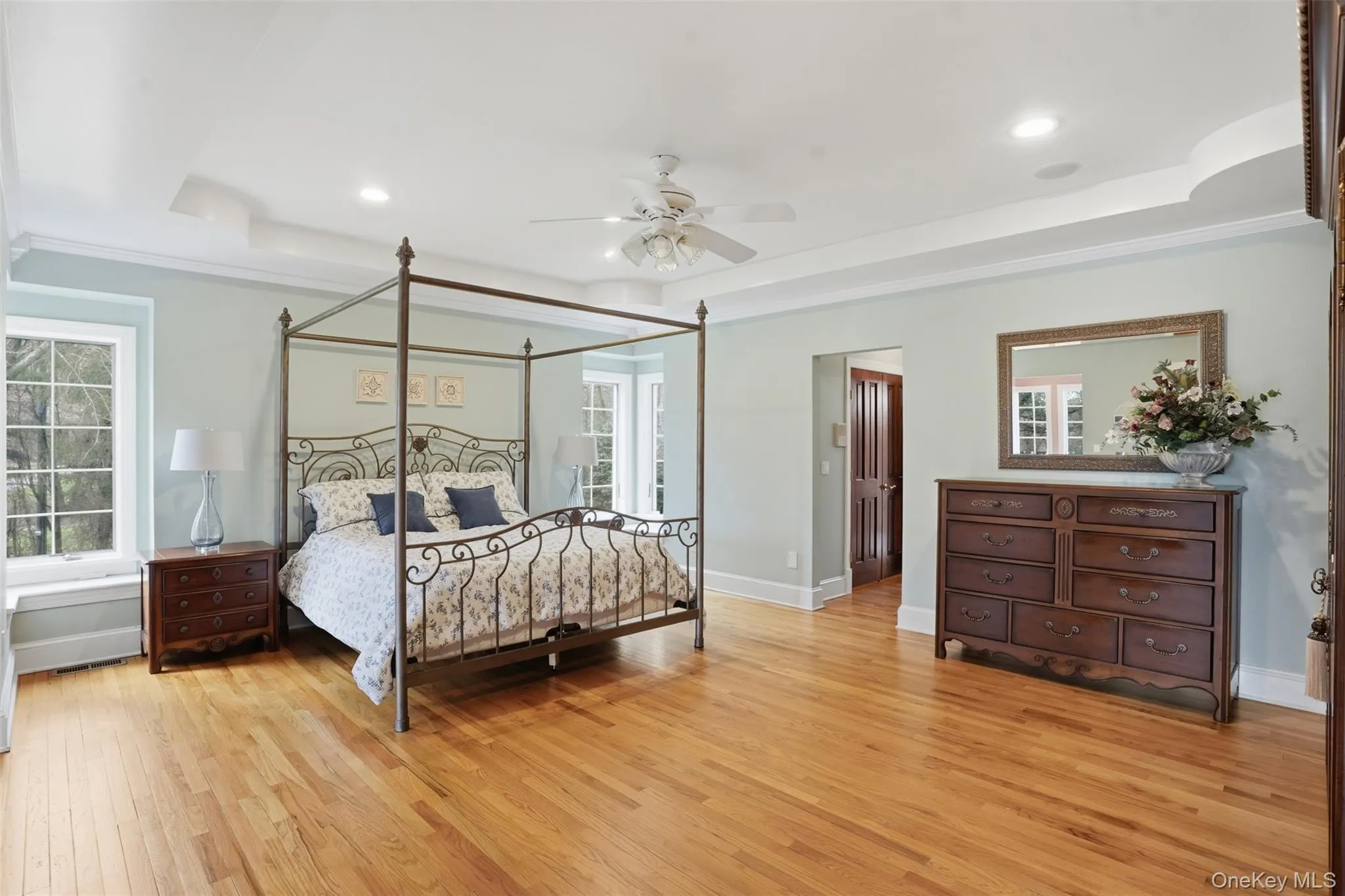 This expansive room features hardwood floors, light blue walls, and a white tray ceiling with recessed lighting This expansive room features hardwood floors, light blue walls, and a white tray ceiling with recessed lighting