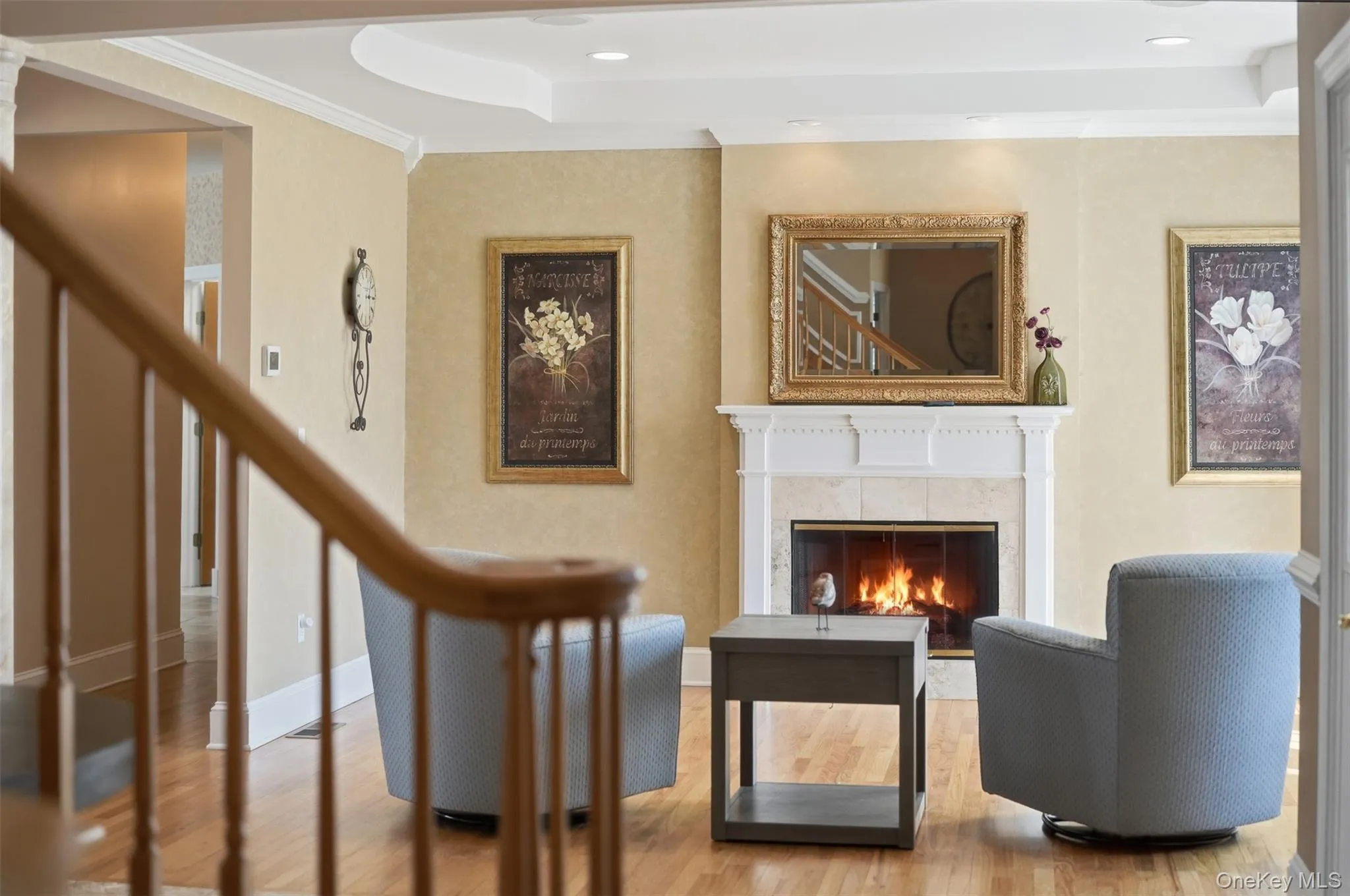 Living room featuring a fireplace with a stone surround and white mantle, warm-toned walls, and hardwood floors Living room featuring a fireplace with a stone surround and white mantle, warm-toned walls, and hardwood floors