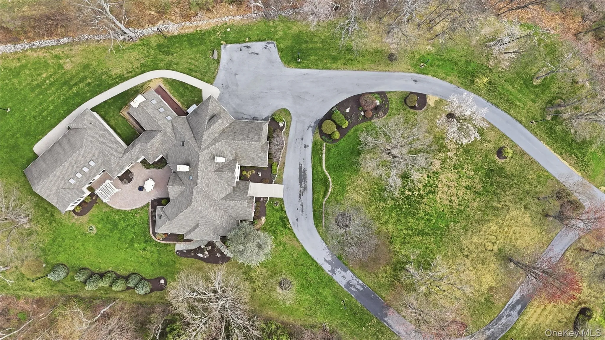 Expansive property with a large driveway, established trees, and a spacious patio area Expansive property with a large driveway, established trees, and a spacious patio area