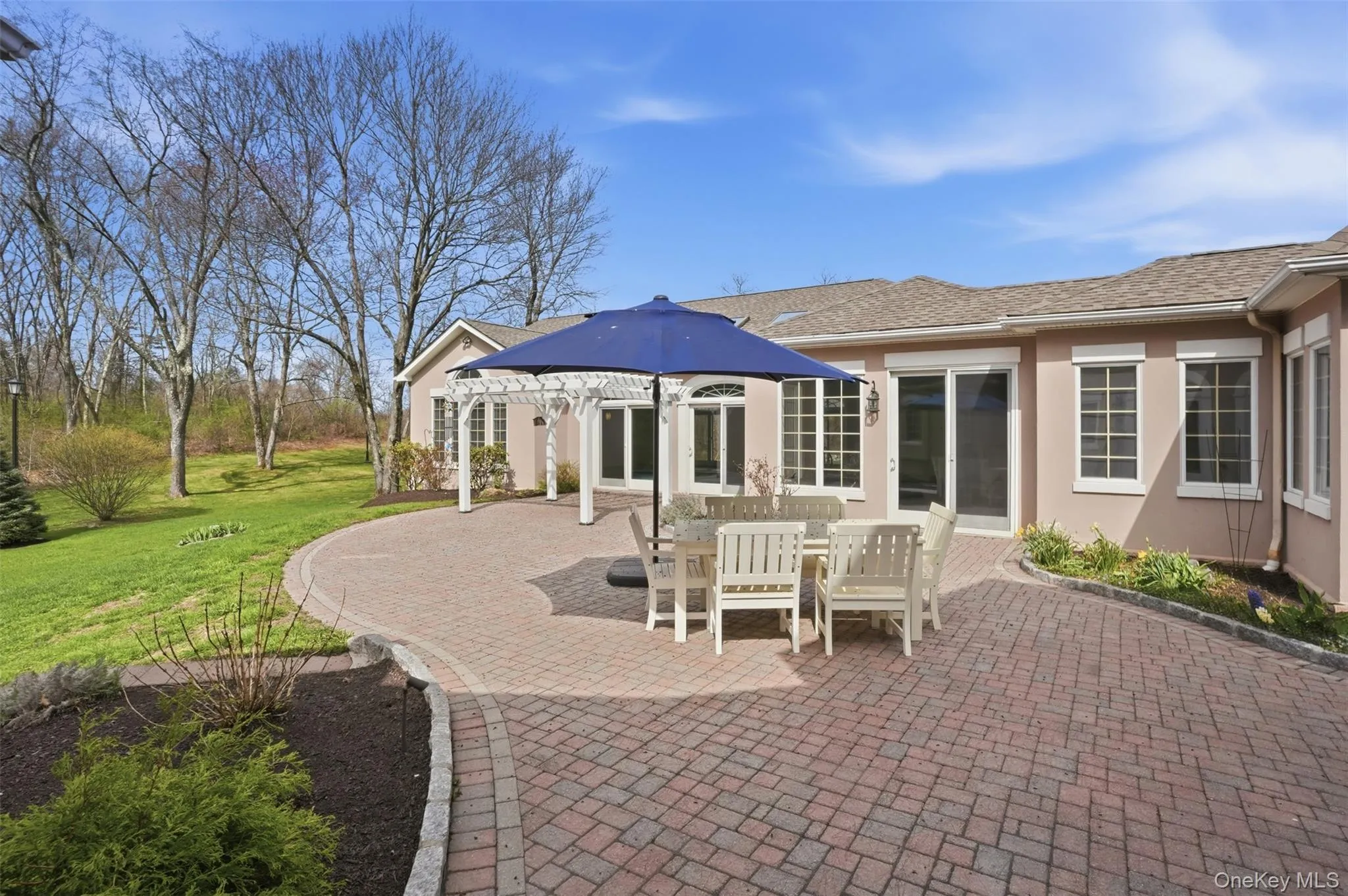 The property features an extensive brick paver patio, a white pergola, and a well-maintained lawn with mature trees The property features an extensive brick paver patio, a white pergola, and a well-maintained lawn with mature trees