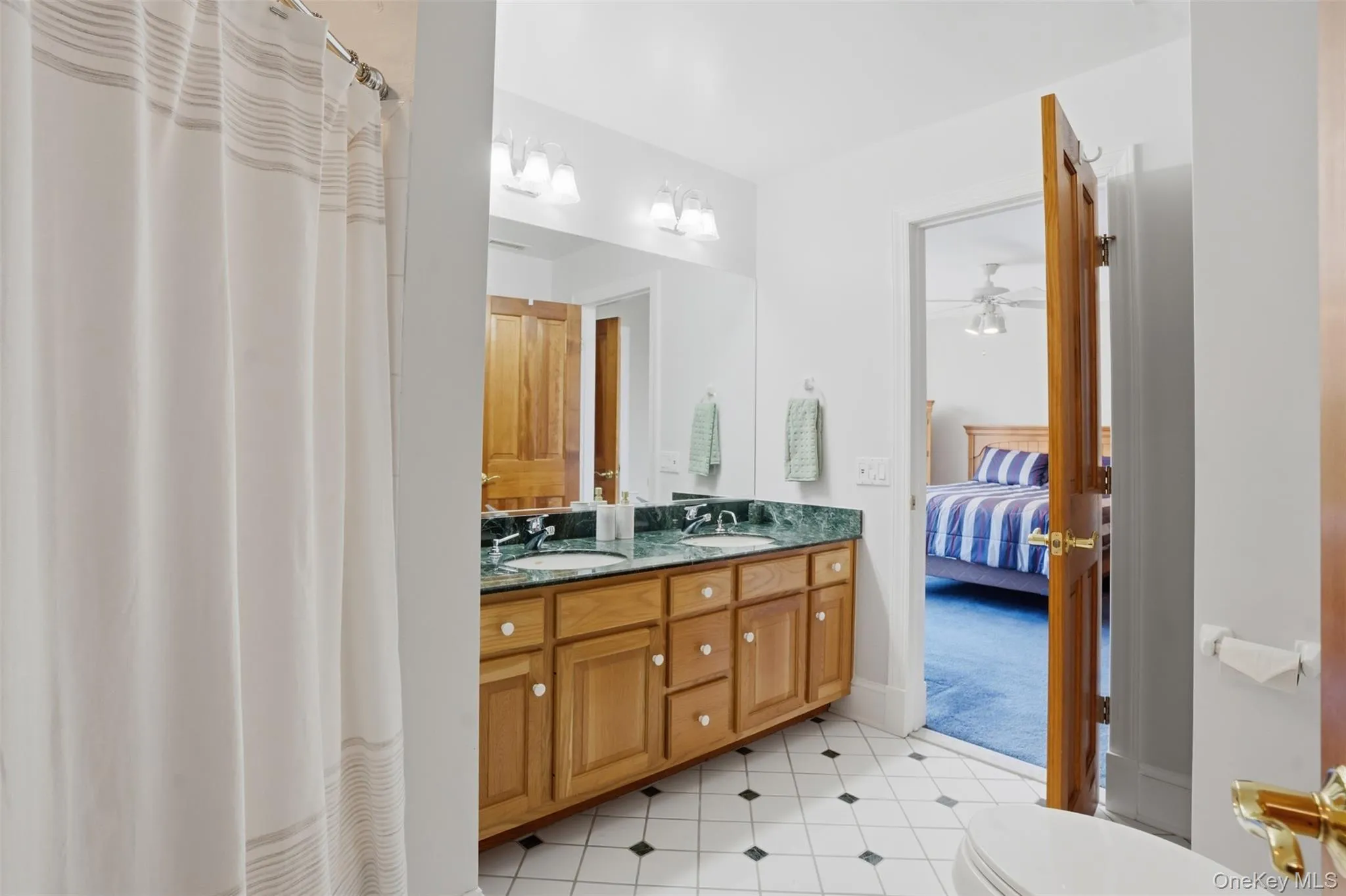 Bathroom featuring a double vanity with a green countertop, wood cabinetry, and a patterned tile floor Bathroom featuring a double vanity with a green countertop, wood cabinetry, and a patterned tile floor