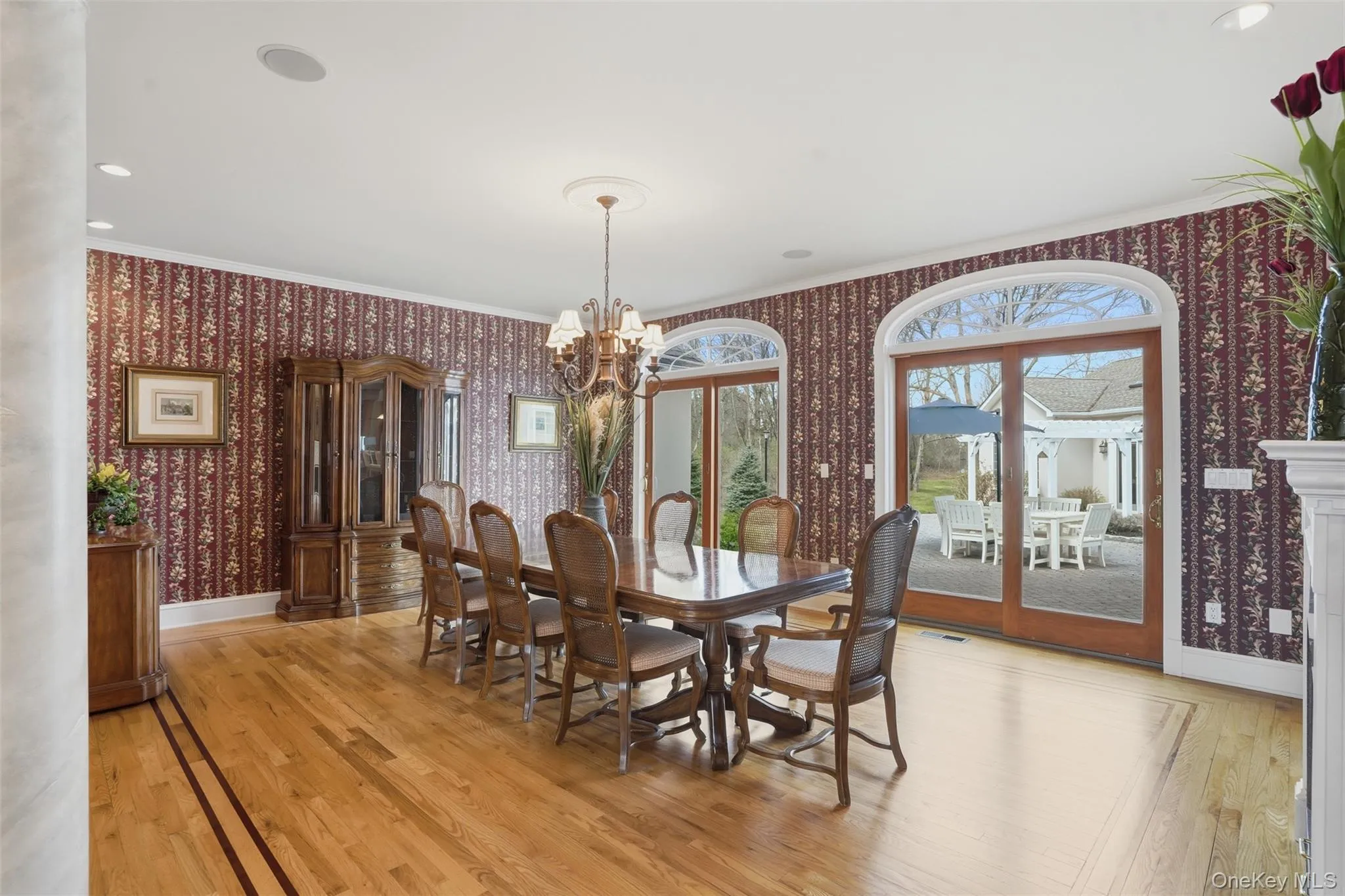This elegant dining area features hardwood floors, decorative wall coverings, and arched glass doors that provide views of the outdoor patio This elegant dining area features hardwood floors, decorative wall coverings, and arched glass doors that provide views of the outdoor patio