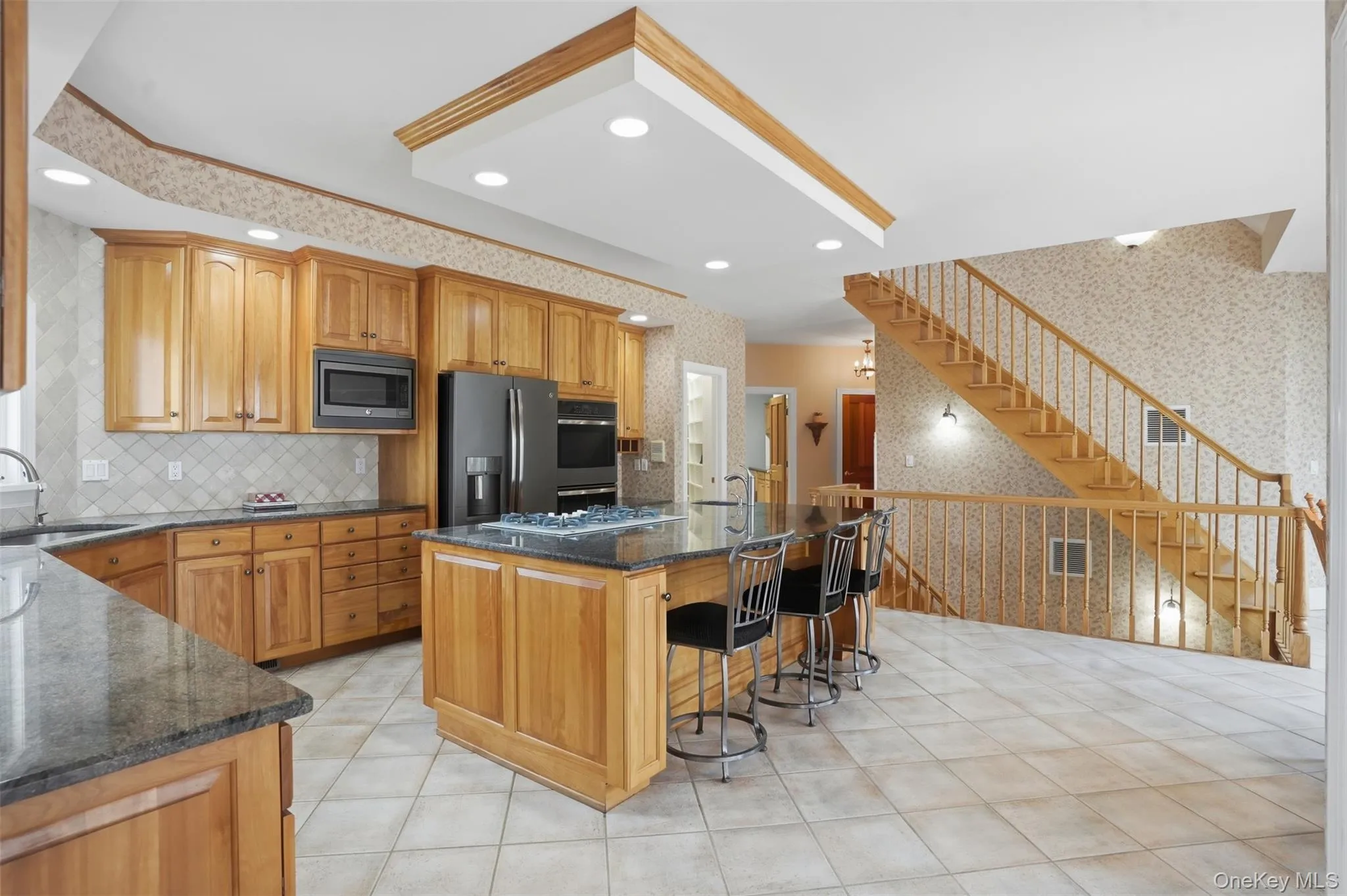 The kitchen features wood cabinetry, dark countertops, and modern appliances The kitchen features wood cabinetry, dark countertops, and modern appliances