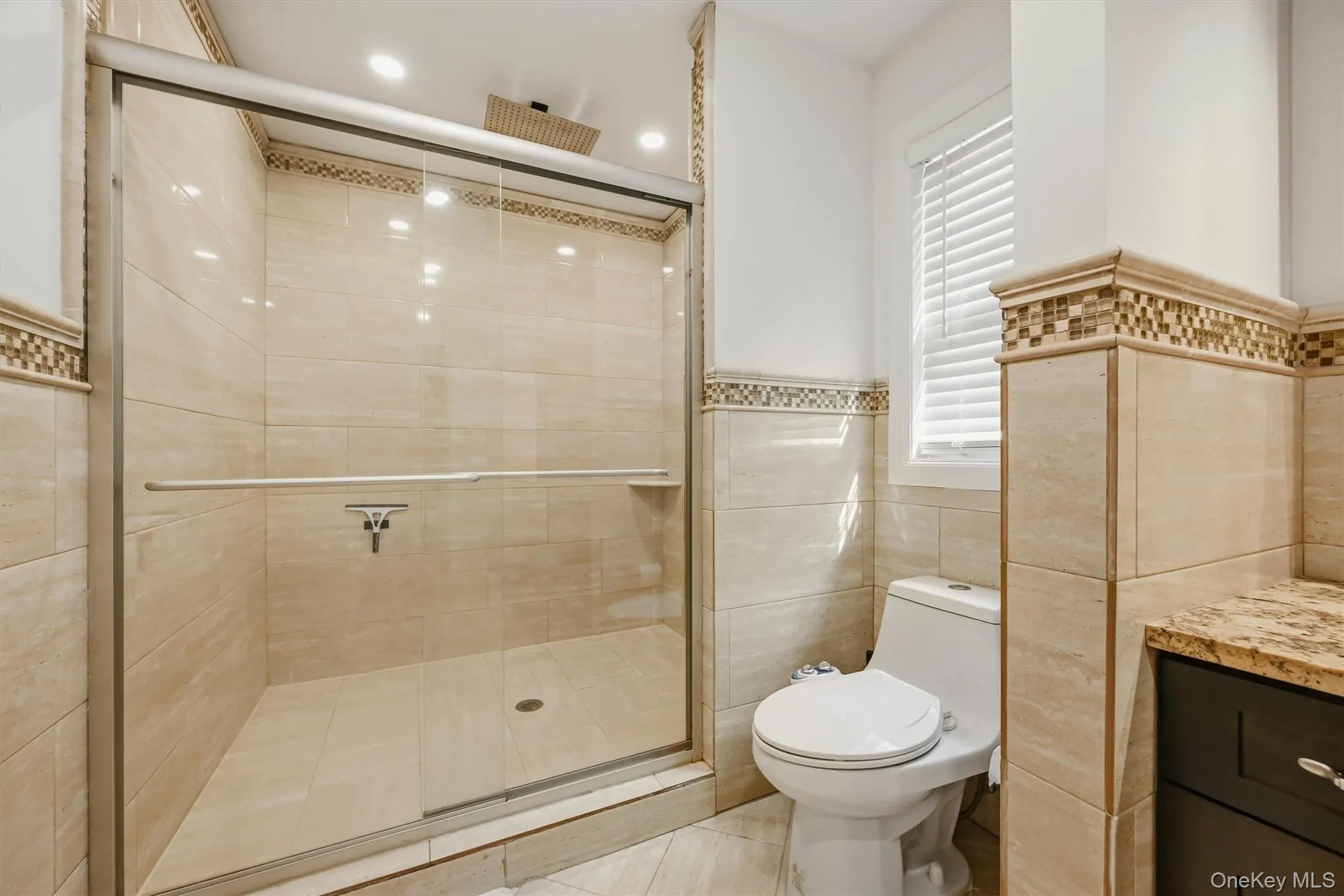 Primary bathroom shower with marble tile. Primary bathroom shower with marble tile.