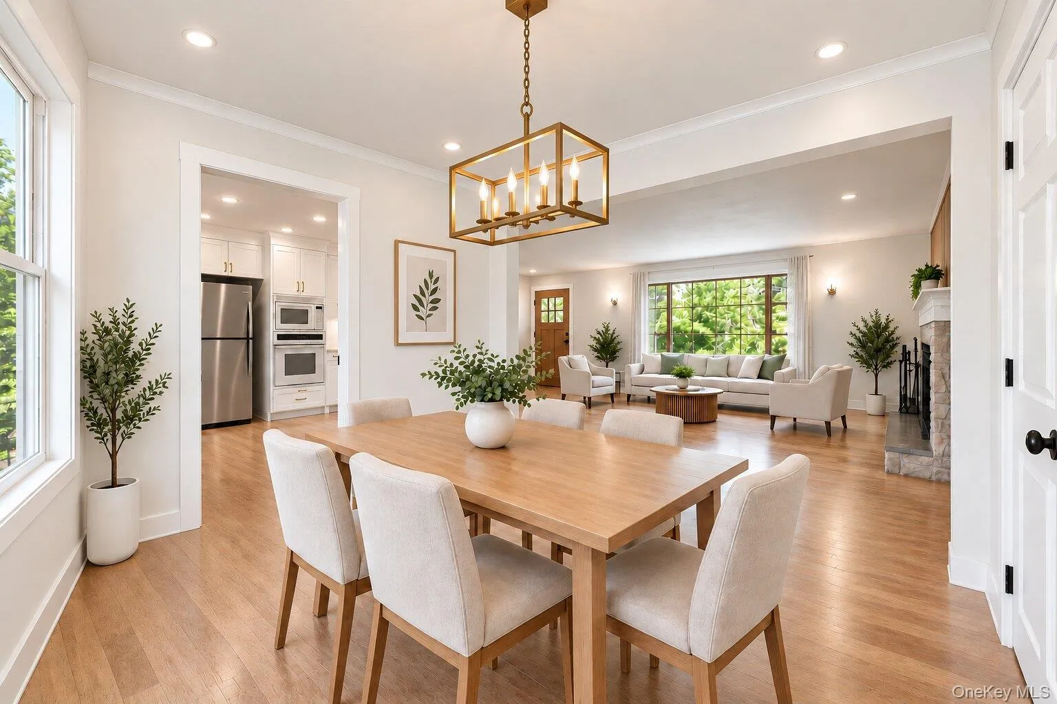 Dining area with wood-finish flooring, a rectangular light wood table, and a brass-finish chandelier Dining area with wood-finish flooring, a rectangular light wood table, and a brass-finish chandelier