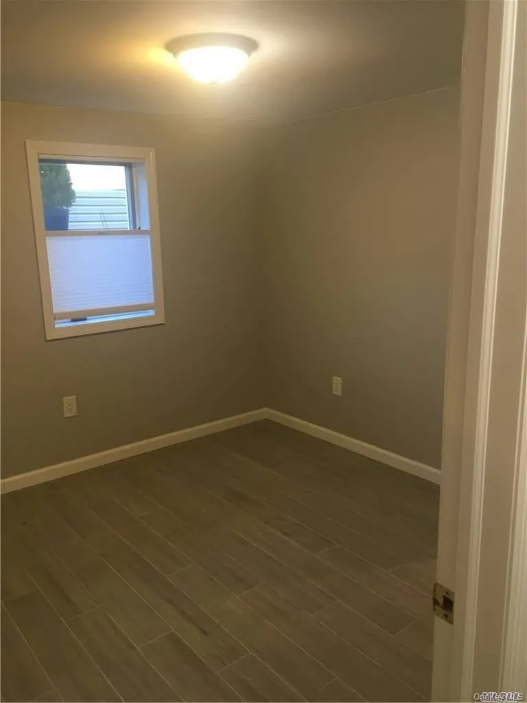 Recessed window with white trim, flush mount ceiling light, and wood-finish flooring Recessed window with white trim, flush mount ceiling light, and wood-finish flooring