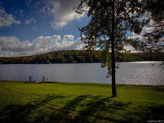 Expansive waterfront property featuring a manicured lawn, mature trees, and a substantial body of water Expansive waterfront property featuring a manicured lawn, mature trees, and a substantial body of water