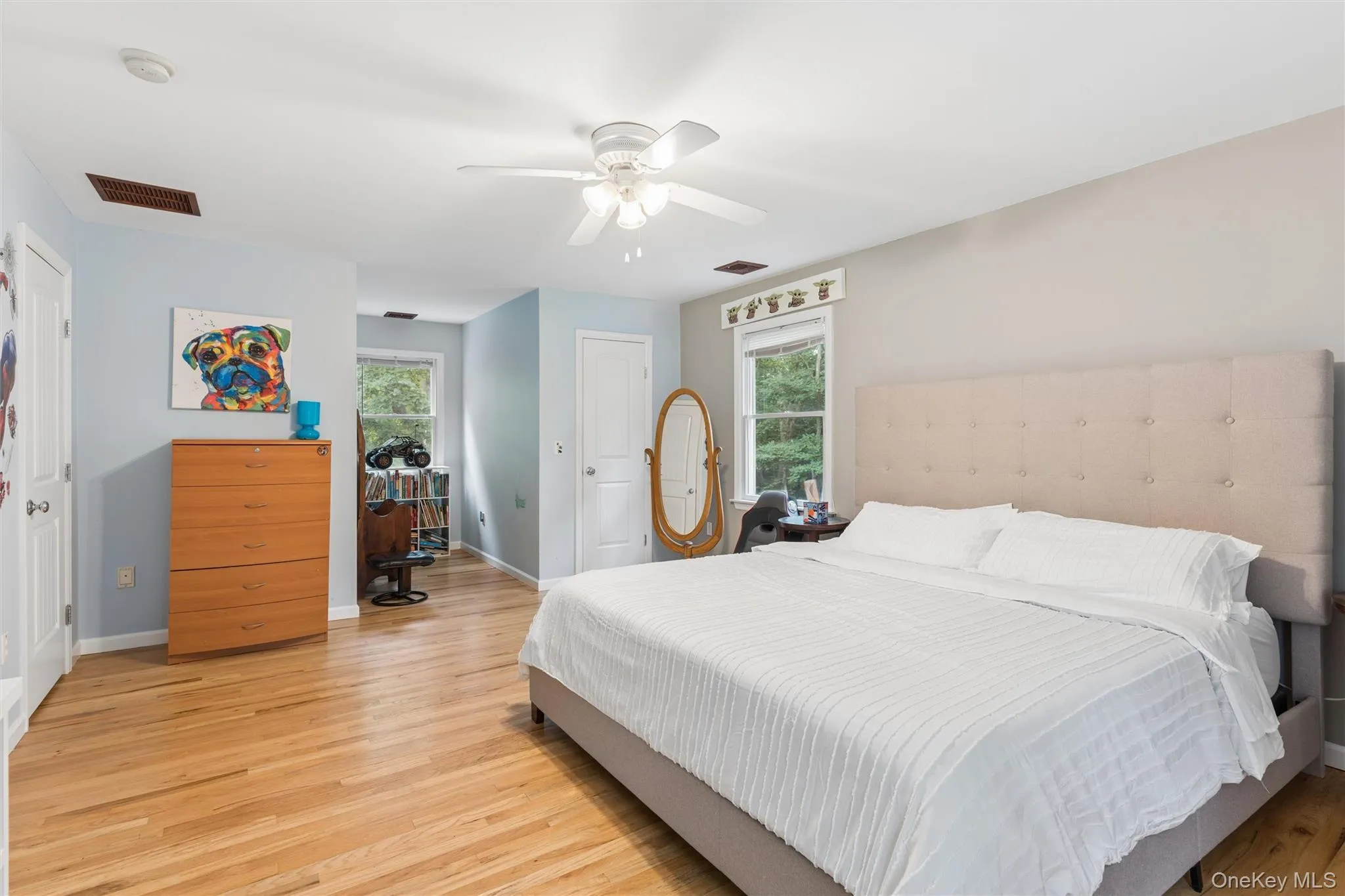 Hardwood flooring throughout, a white ceiling fan, and multiple windows providing natural light Hardwood flooring throughout, a white ceiling fan, and multiple windows providing natural light