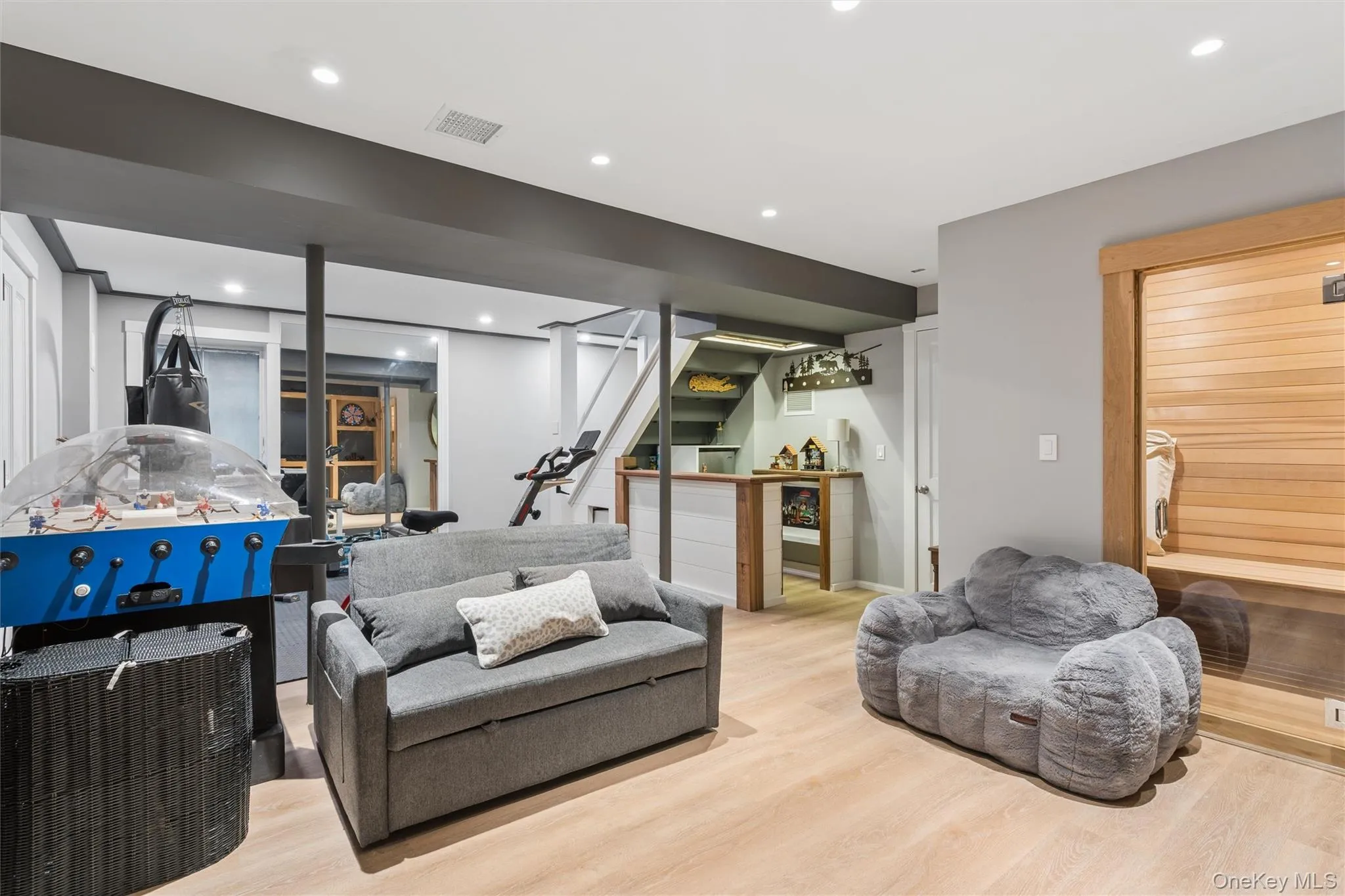 Light wood-finish flooring, built-in dry sauna, recessed lighting, and a white and wood-finish accent bar Light wood-finish flooring, built-in dry sauna, recessed lighting, and a white and wood-finish accent bar