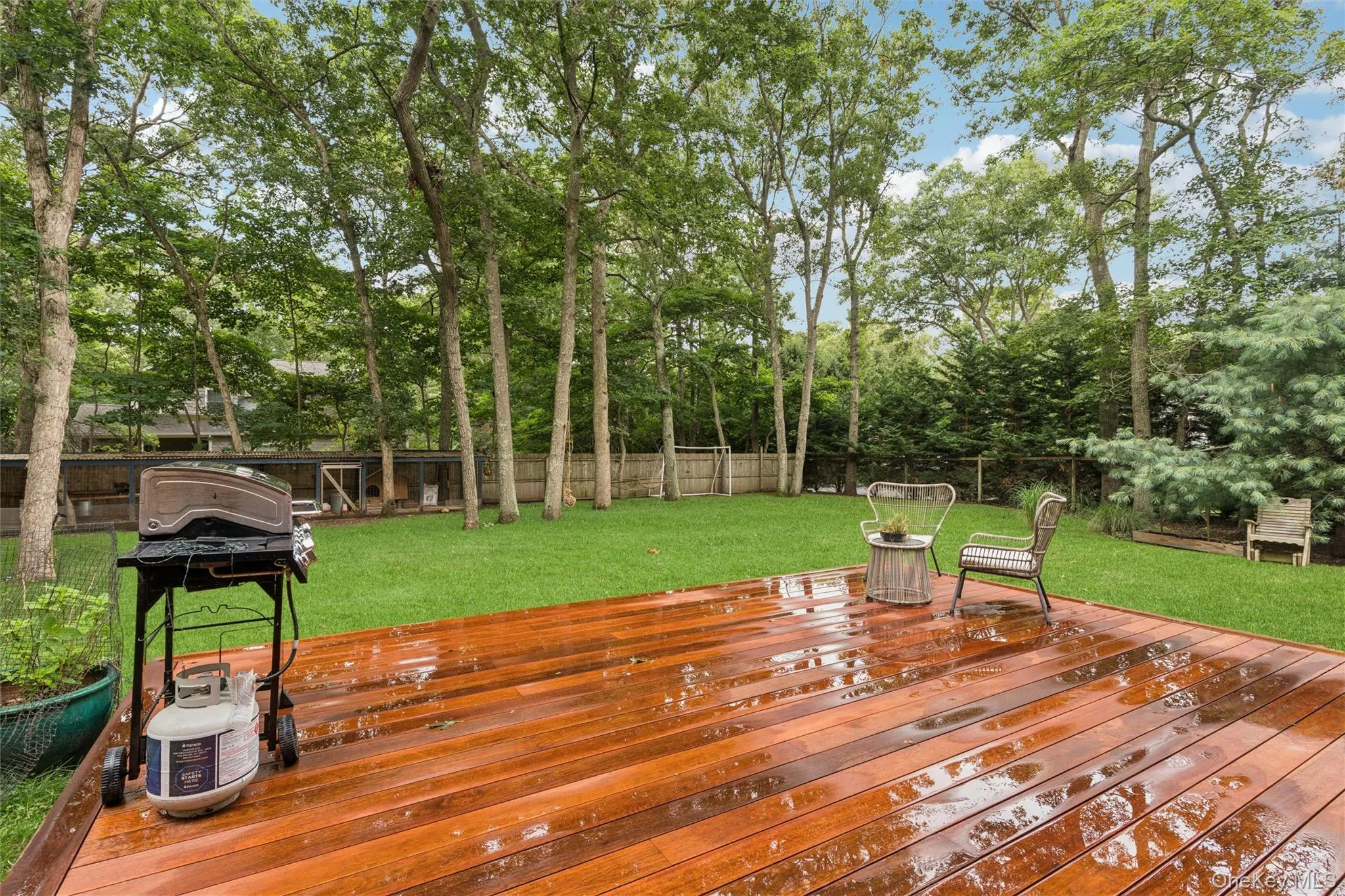 Spacious wood-finish deck with a manicured lawn and mature trees Spacious wood-finish deck with a manicured lawn and mature trees