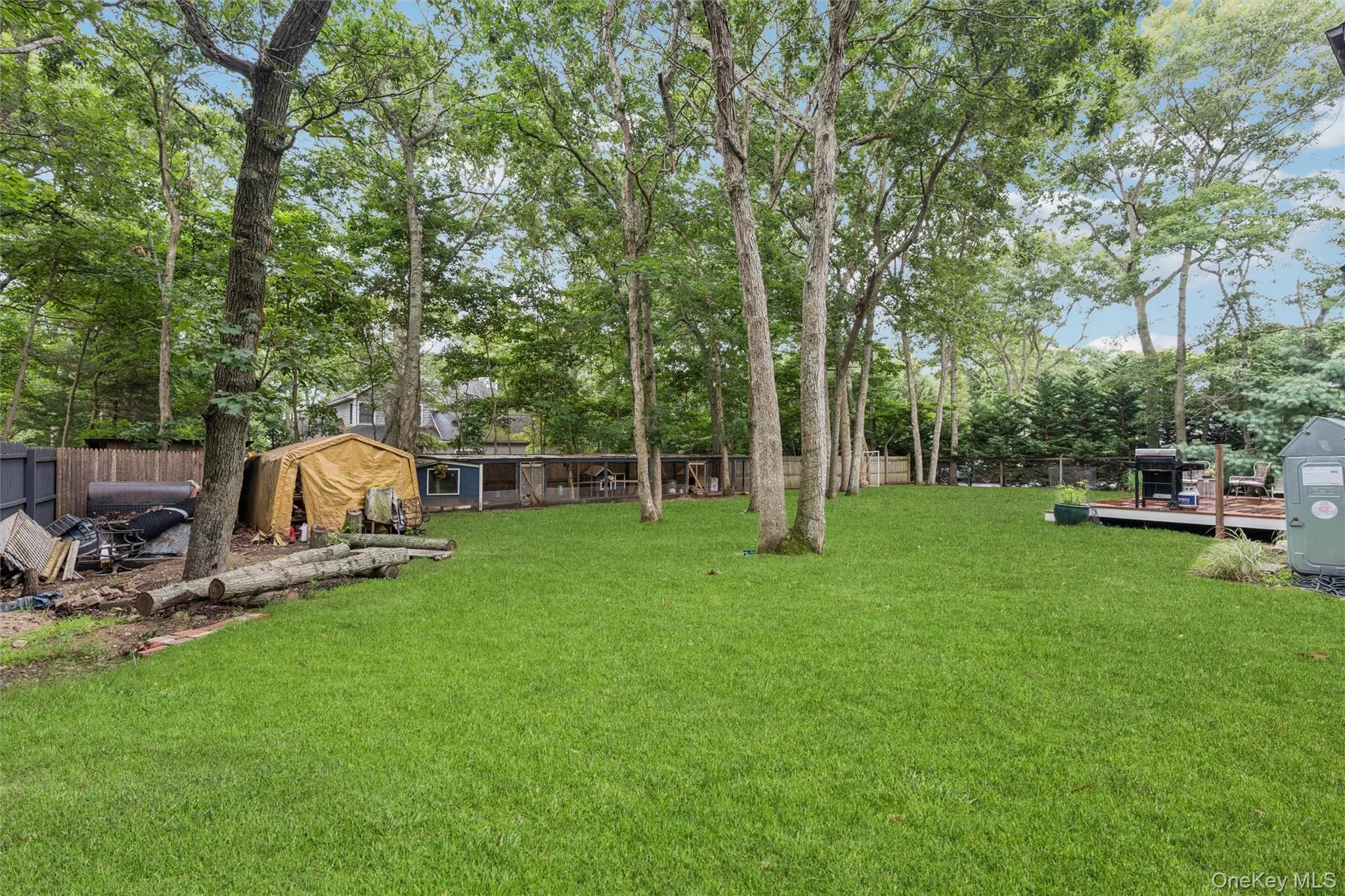 Expansive backyard featuring a manicured lawn, mature trees, and a wooden deck Expansive backyard featuring a manicured lawn, mature trees, and a wooden deck